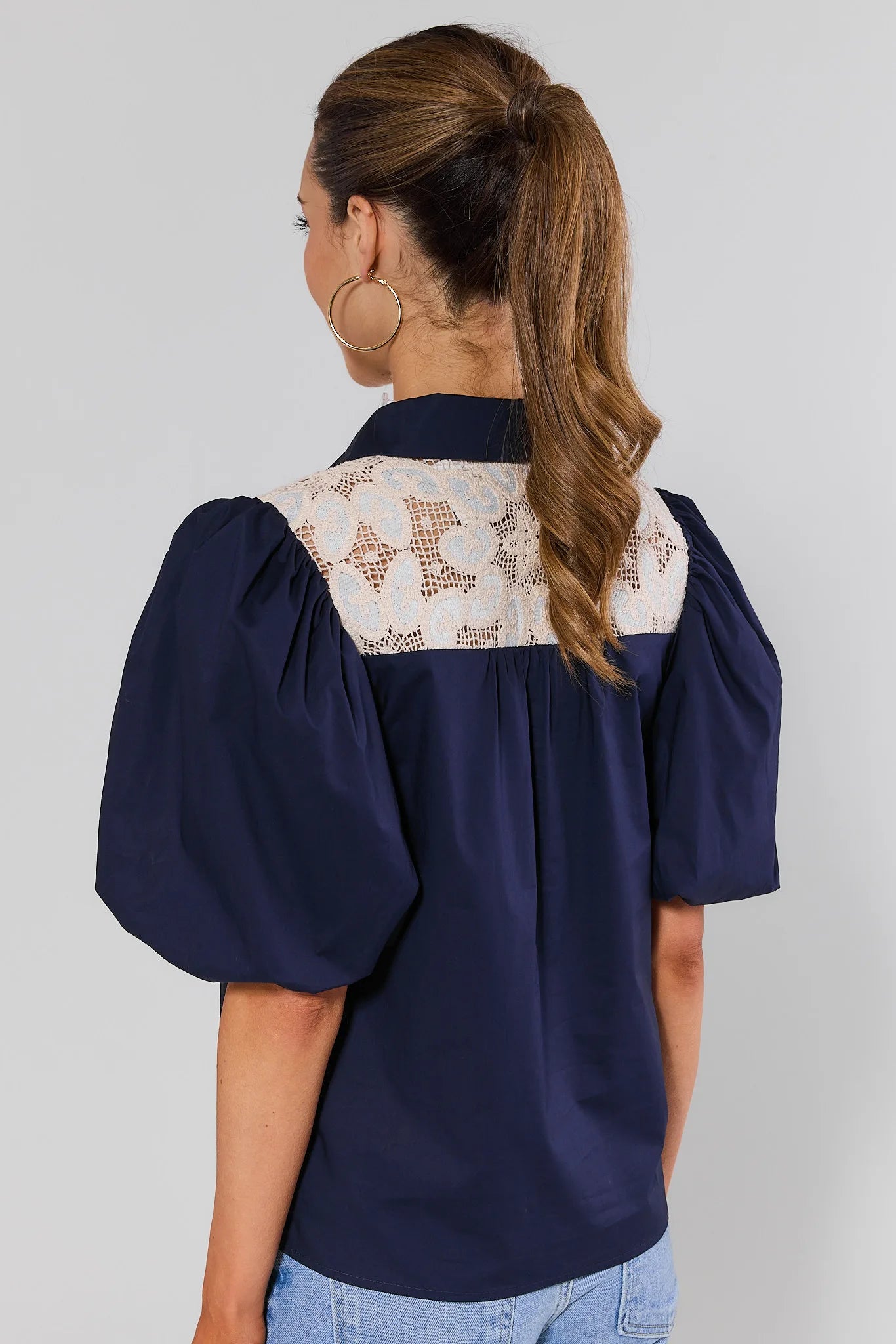 Navy blue blouse with white embroidered details on a plain background