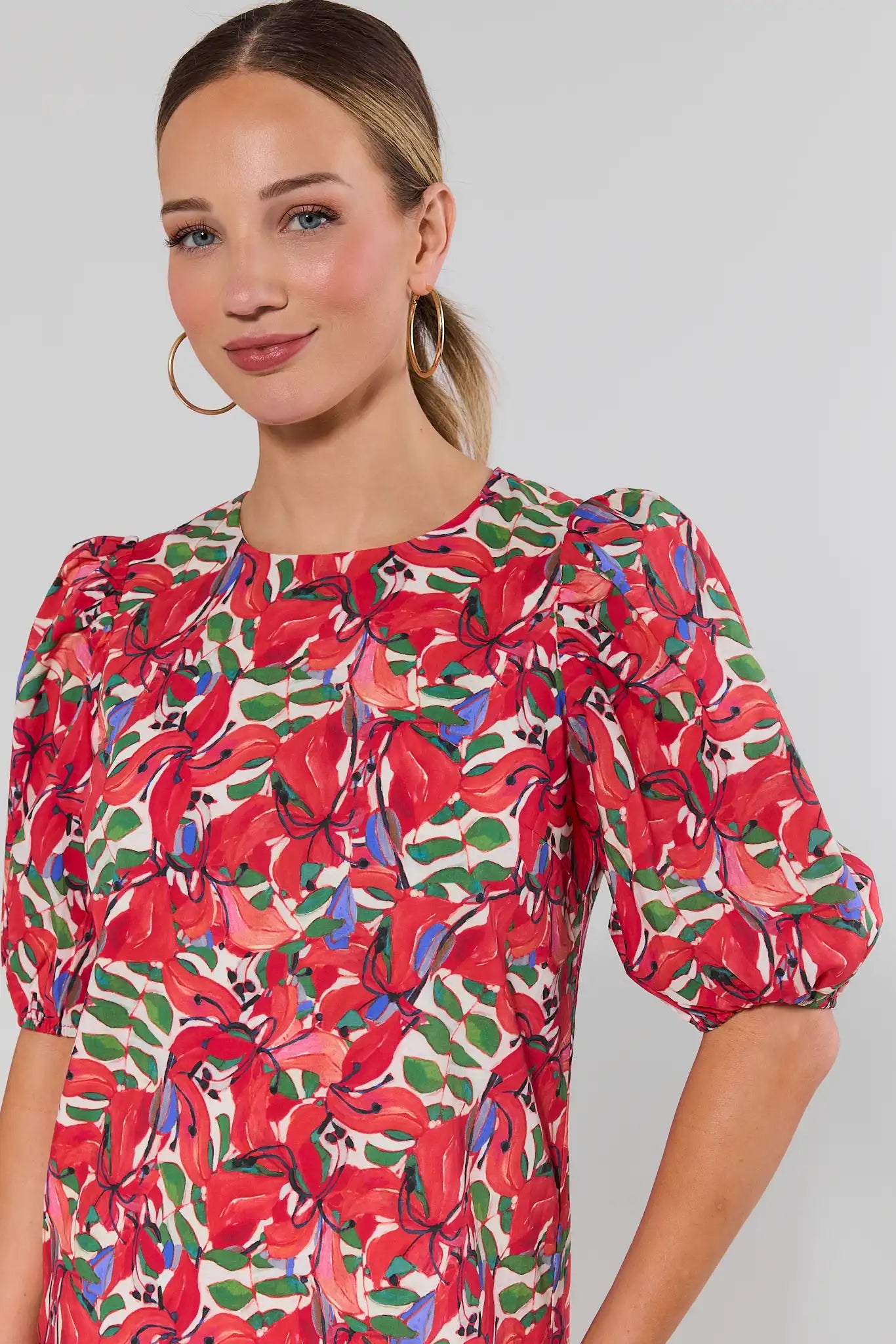 close up Woman wearing a colorful floral dress against a plain background