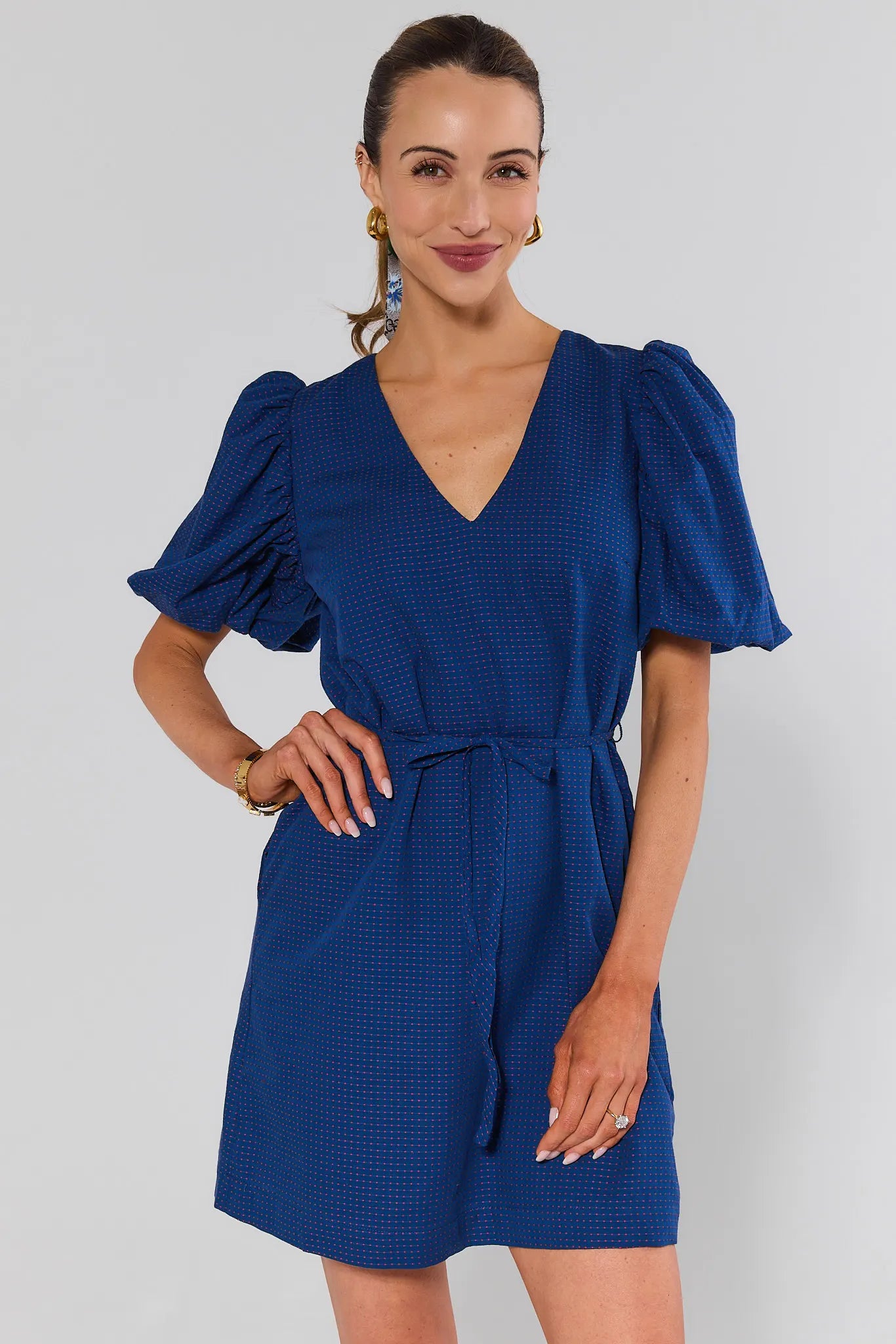 Woman wearing a blue dress with puff sleeves against a white background