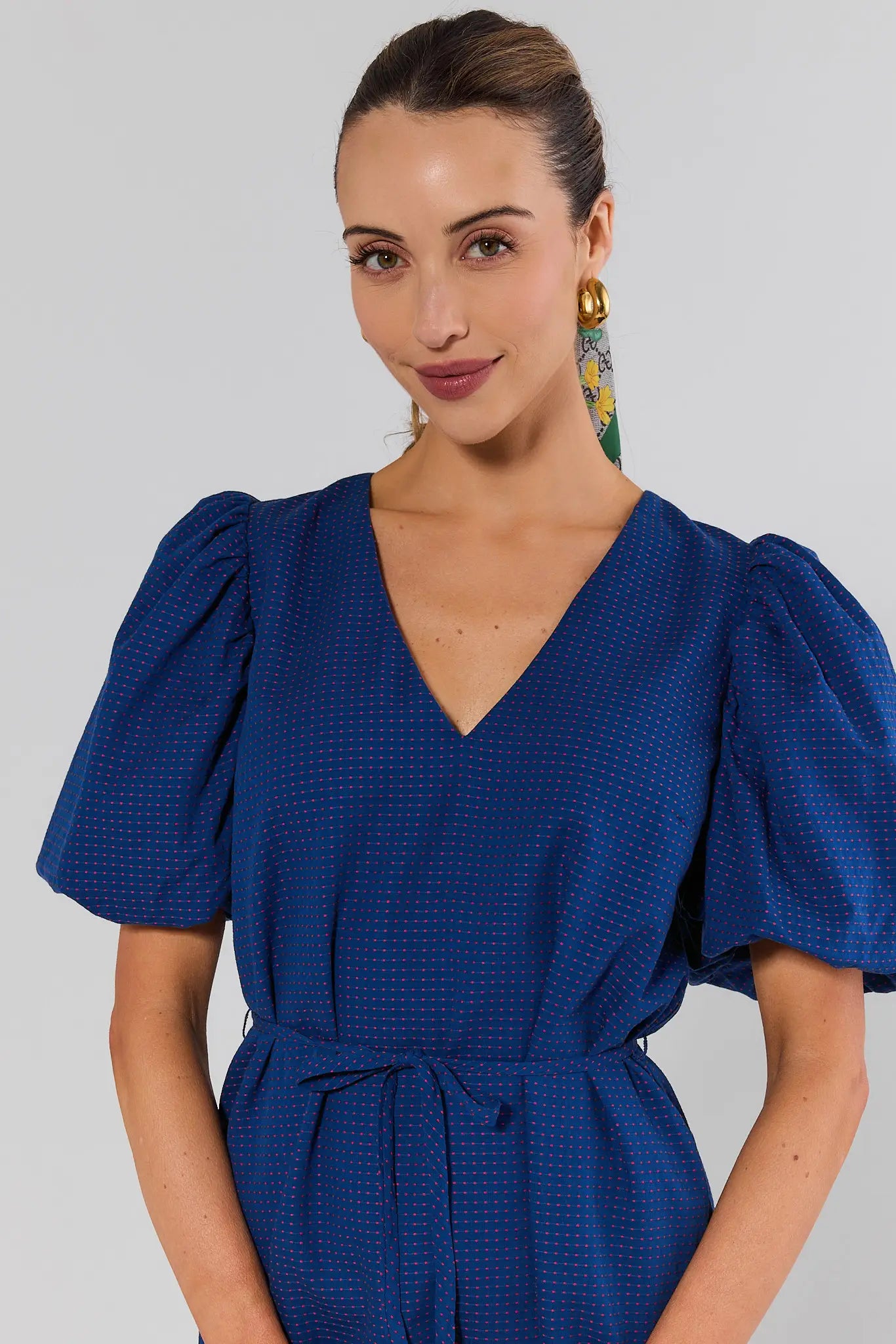 close up Woman wearing a blue dress with puffed sleeves against a gray background