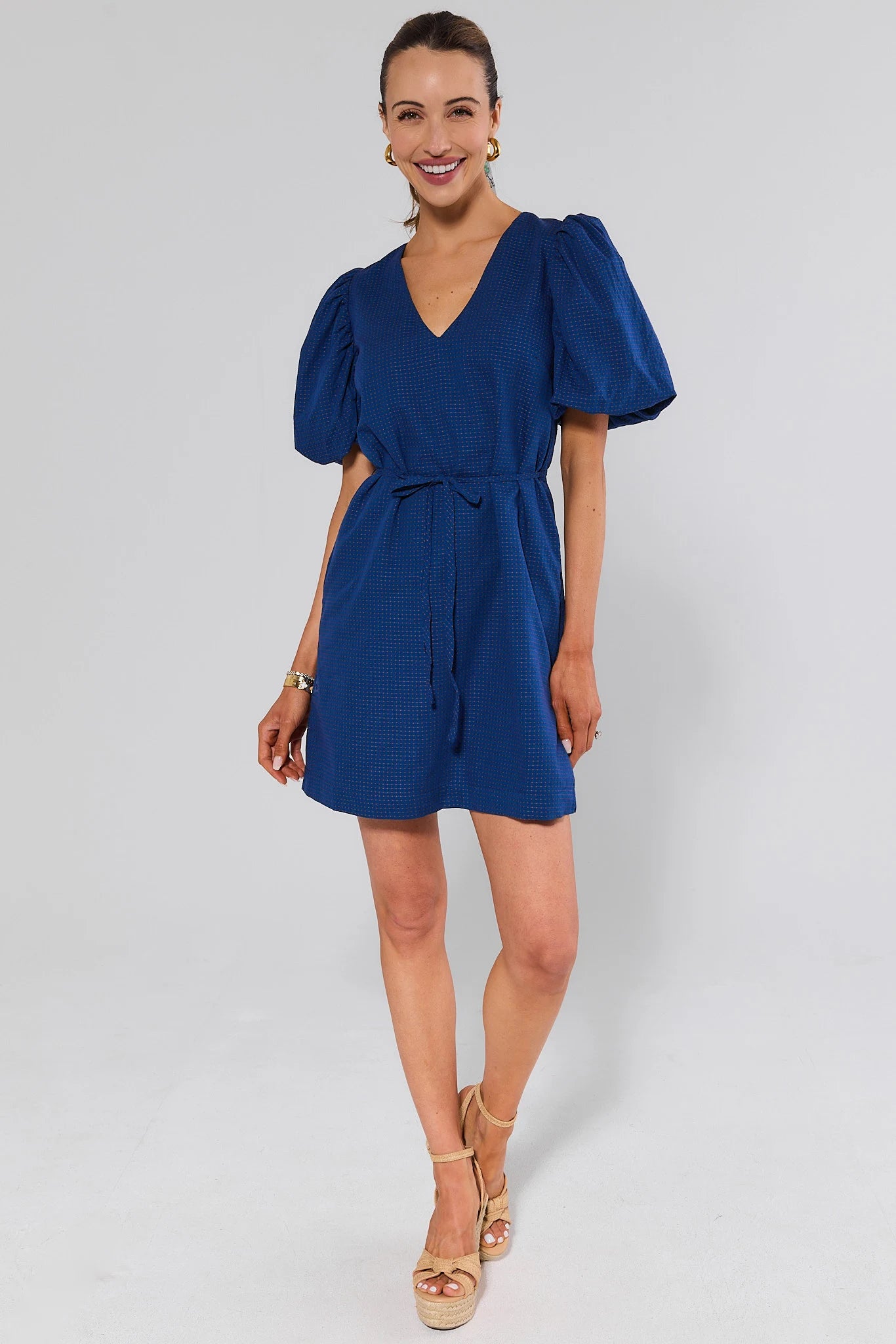 Woman wearing a blue dress and wedges on a white background