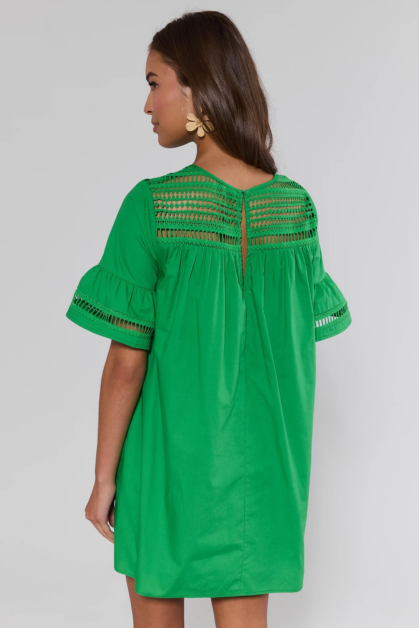 Green dress with lace detailing on a plain background standing