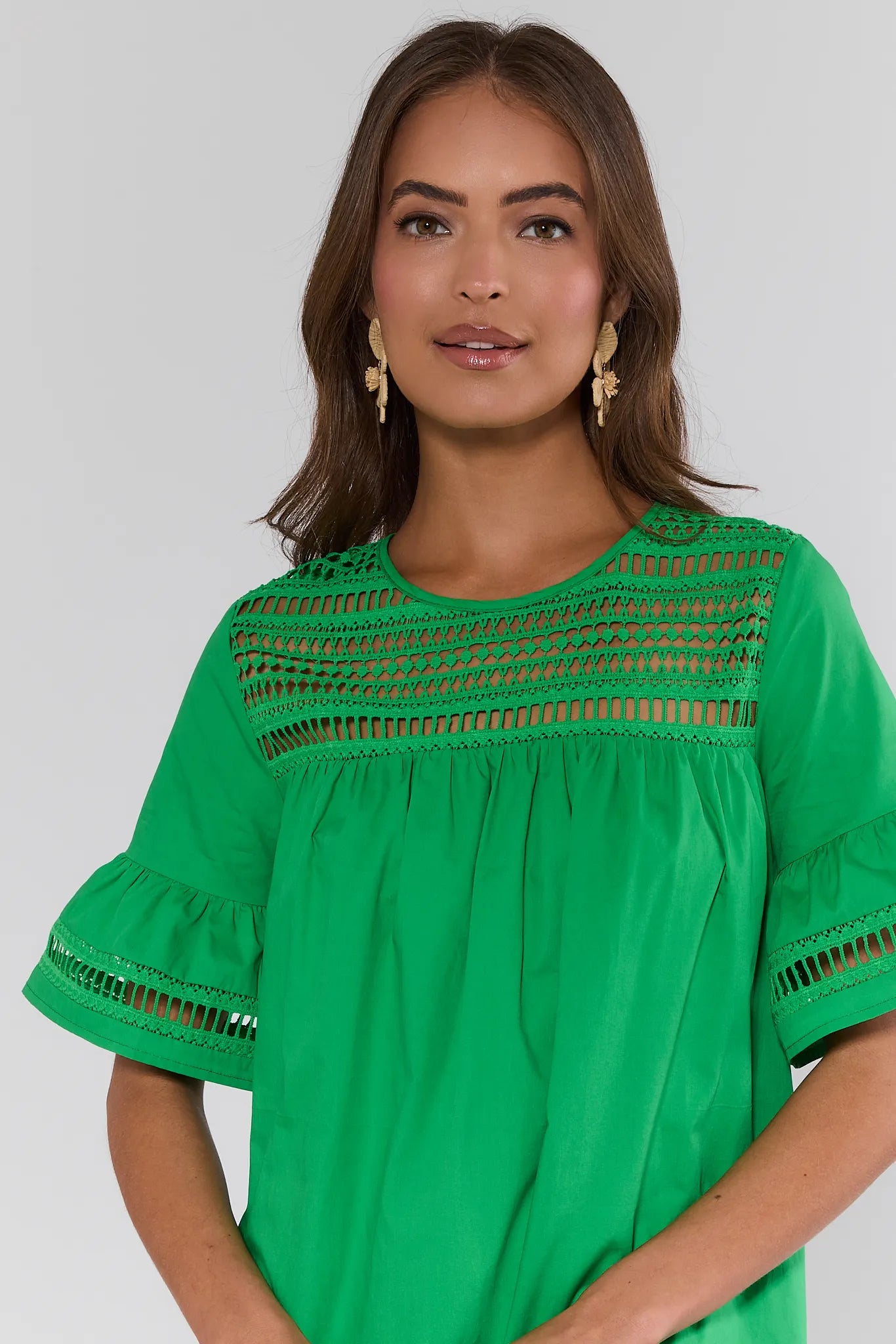 close up Woman wearing a green blouse with intricate detailing on a plain background