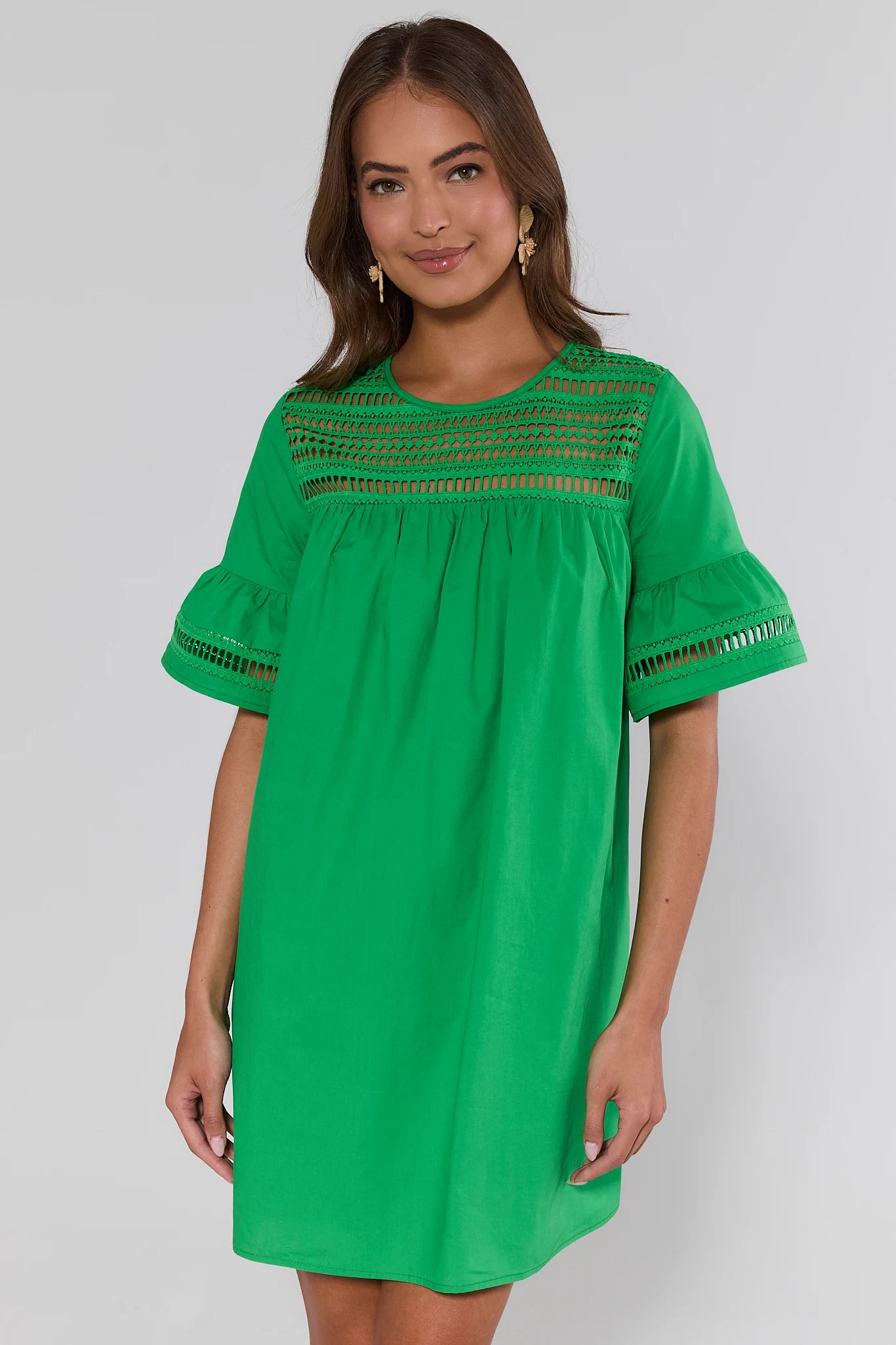 Woman wearing a green dress with lace details on a white background