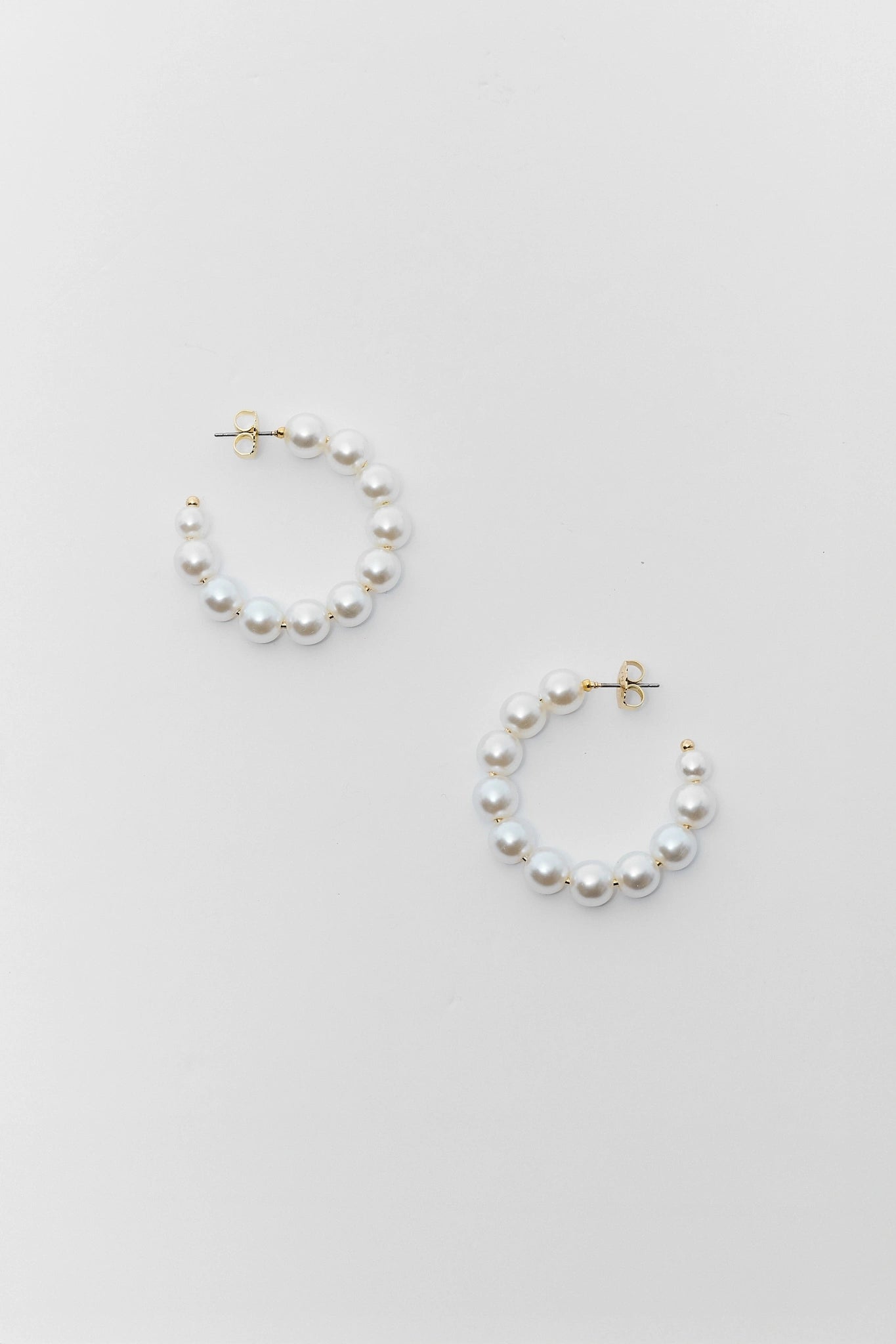 Pair of pearl hoop earrings on a light gray background