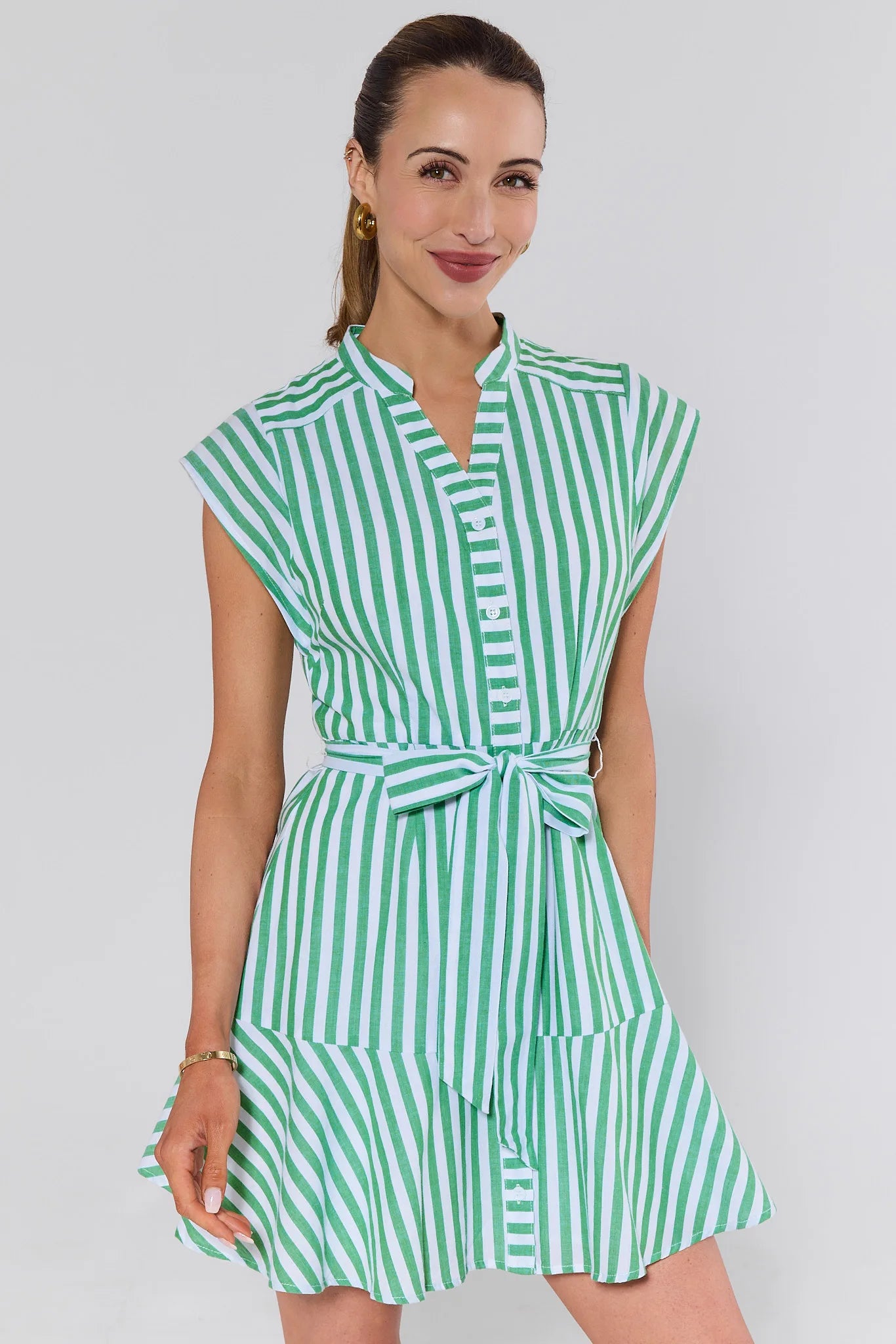 Woman wearing a green and white striped dress against a plain background