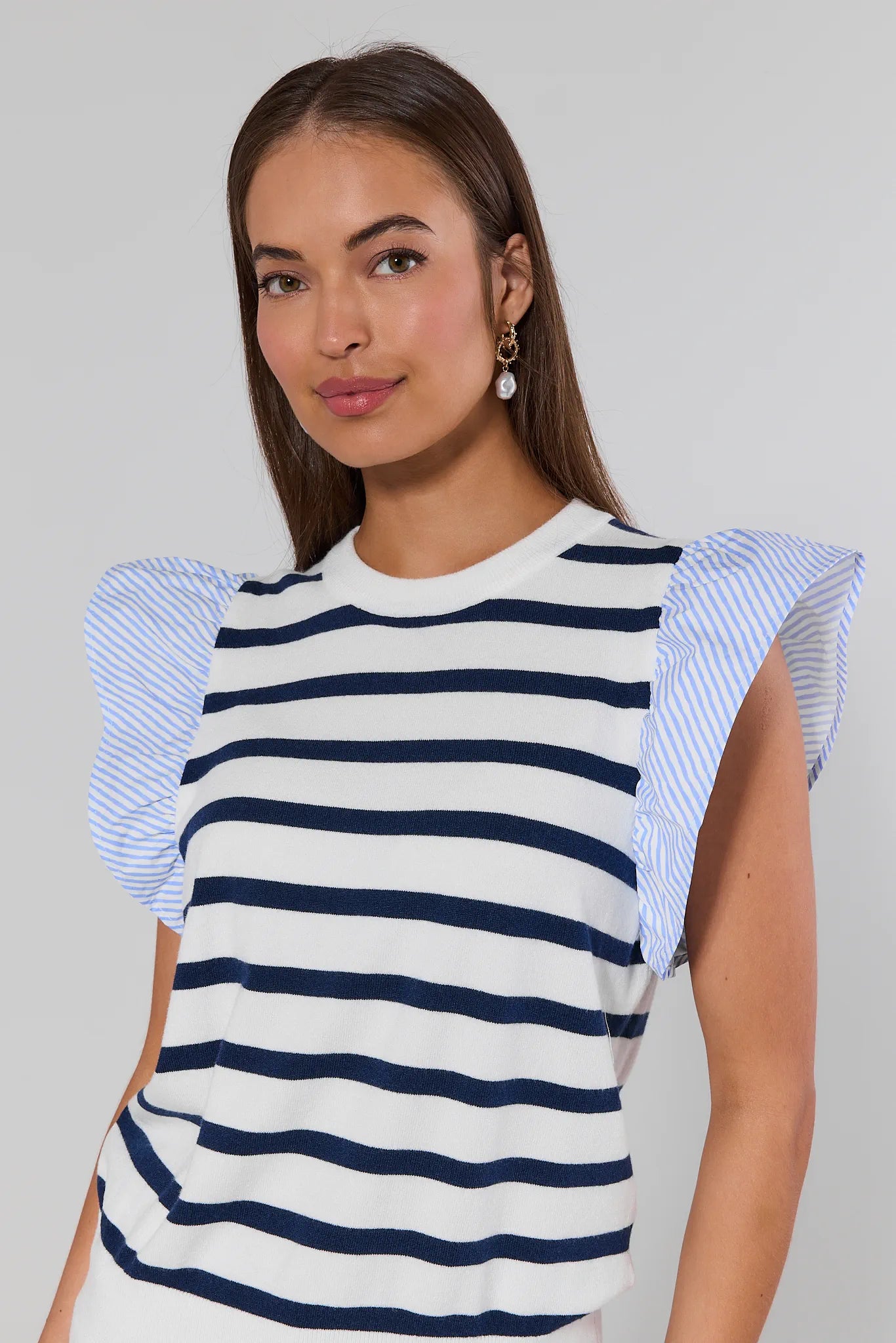 Woman wearing a striped top with ruffled sleeves against a plain background