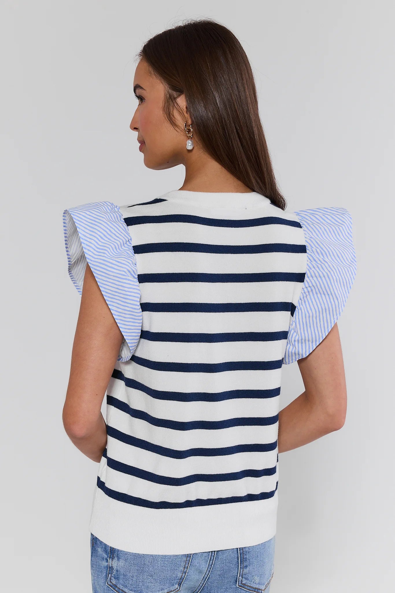 Woman wearing a striped shirt with ruffled sleeves on a plain background