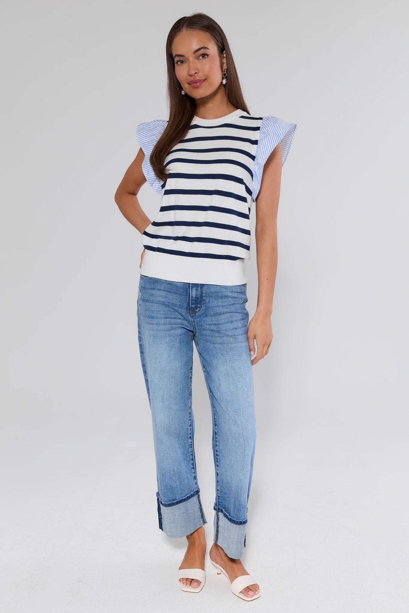 Woman wearing a striped shirt and jeans on a plain background