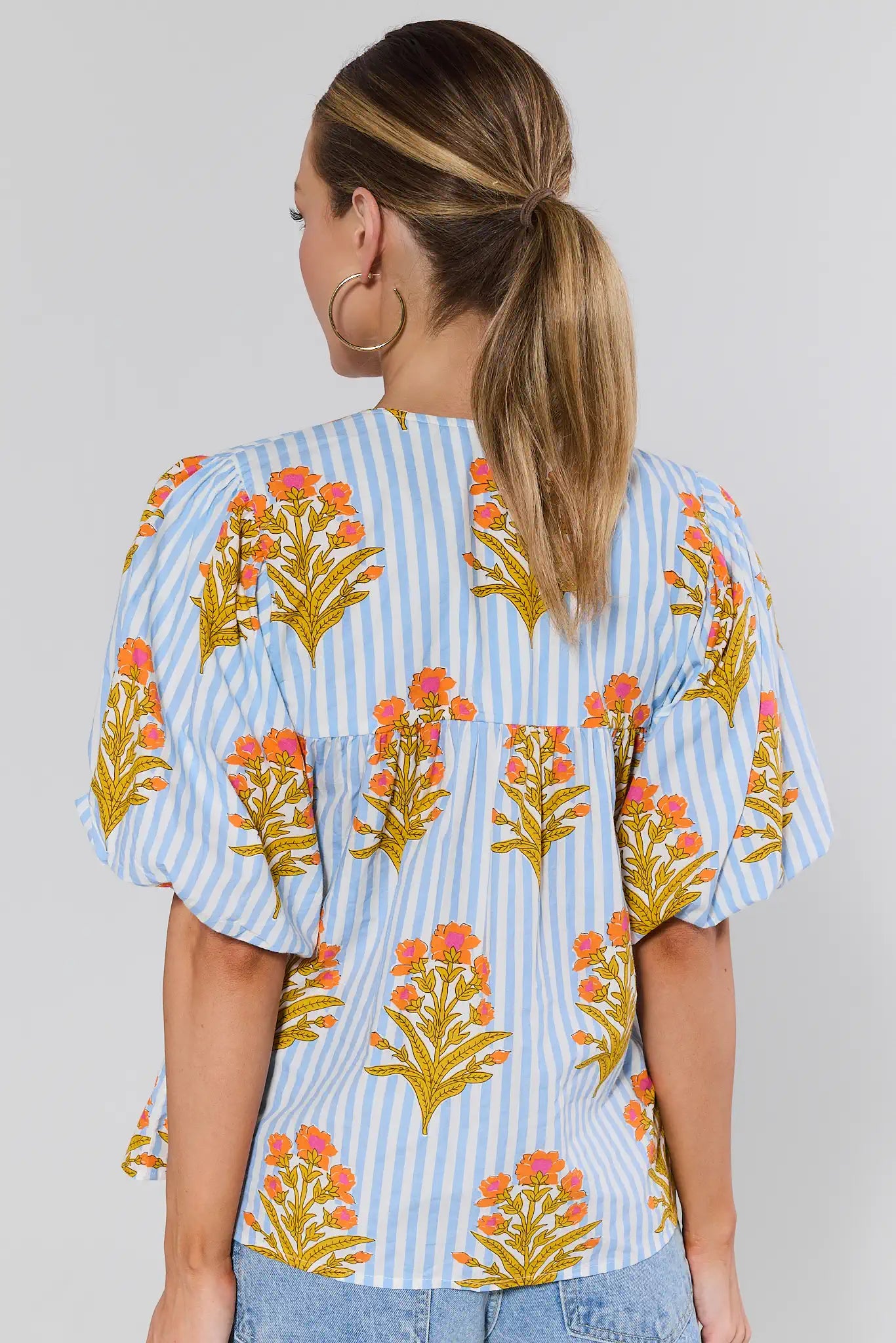 Woman wearing a floral and striped blouse with a plain background