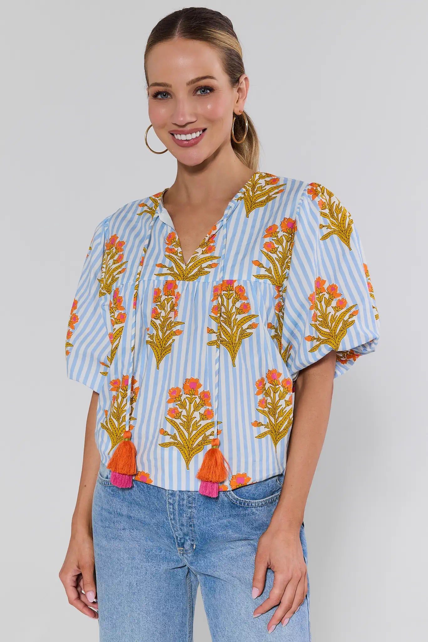 Woman wearing a colorful floral blouse with blue stripes on a plain background