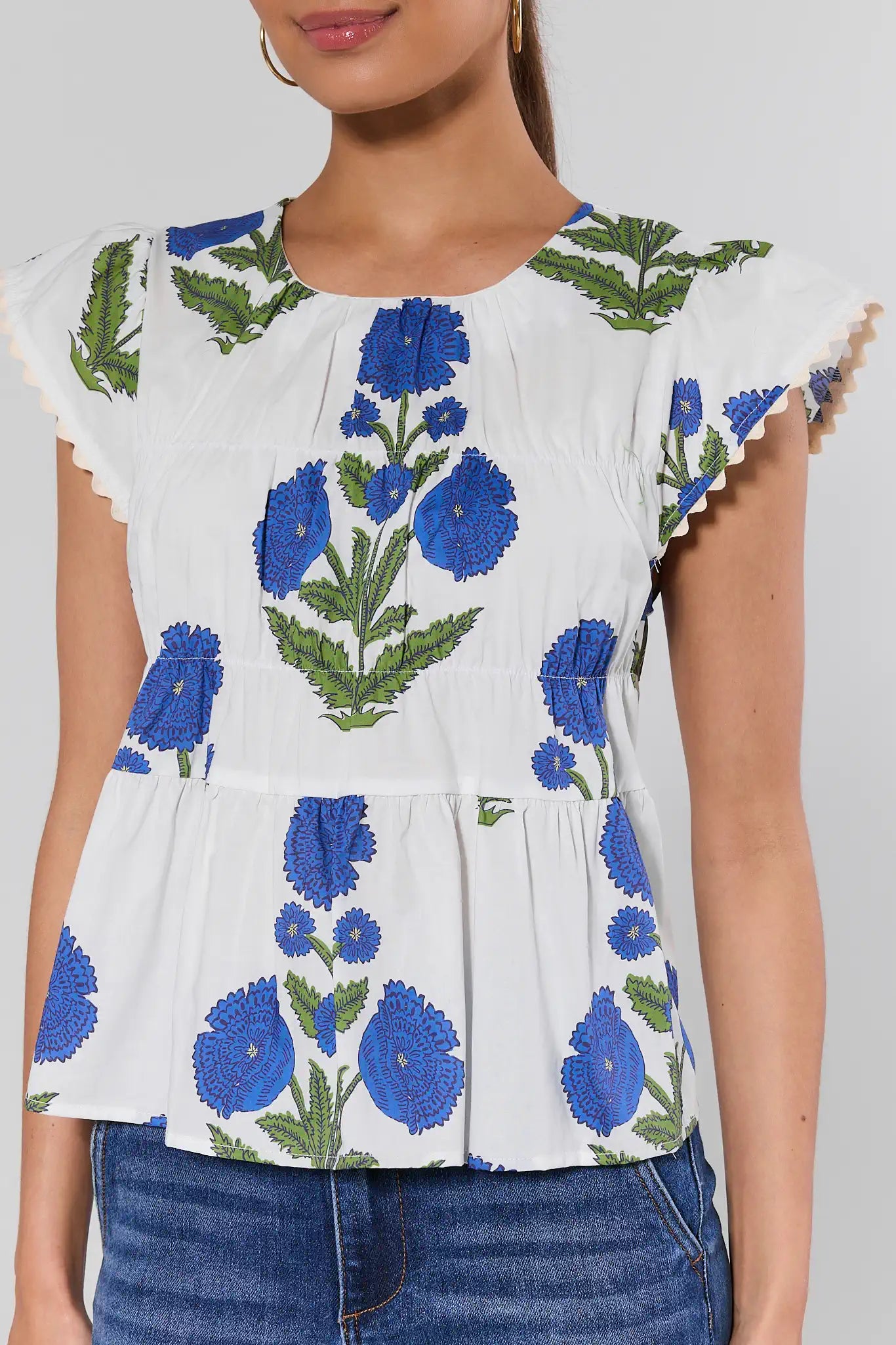 White blouse with blue floral embroidery on a plain background
