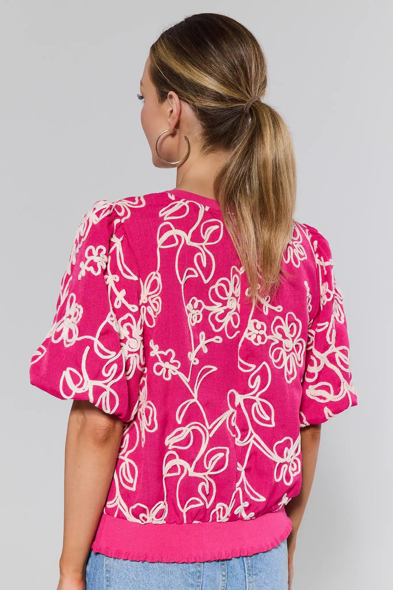 Woman wearing a pink floral blouse against a plain background