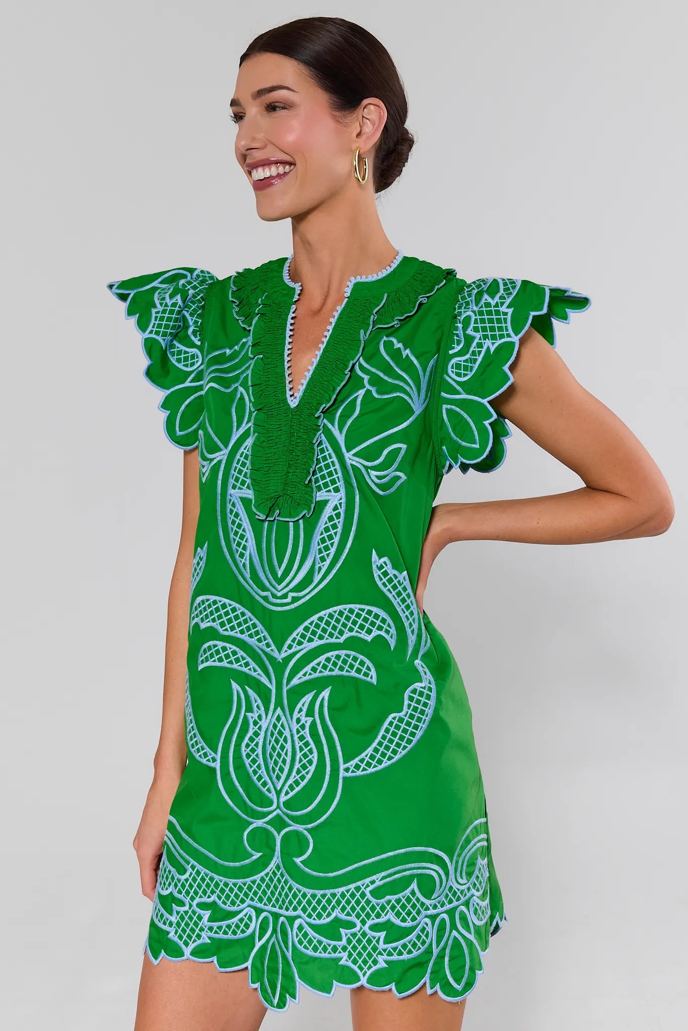 Woman wearing a green dress with white floral patterns on a plain background