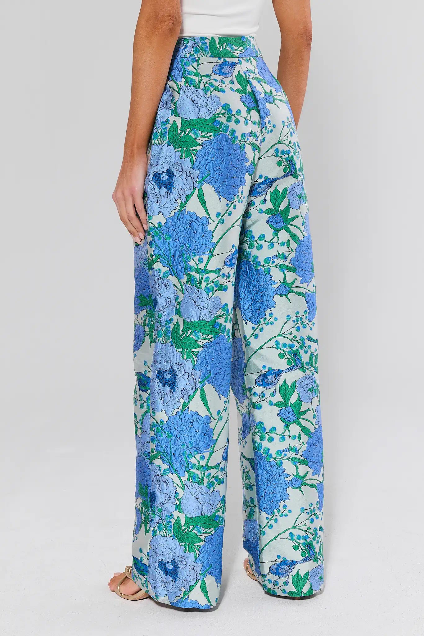 Floral patterned pants worn by a person on a plain background