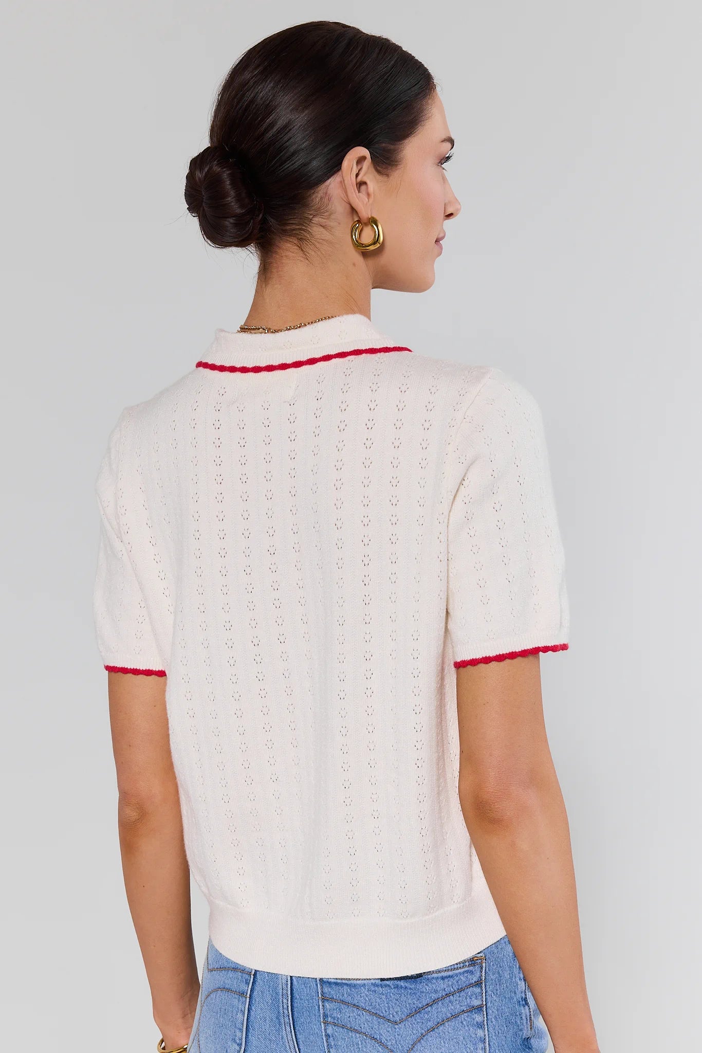 Woman wearing a white top with red trim on a background