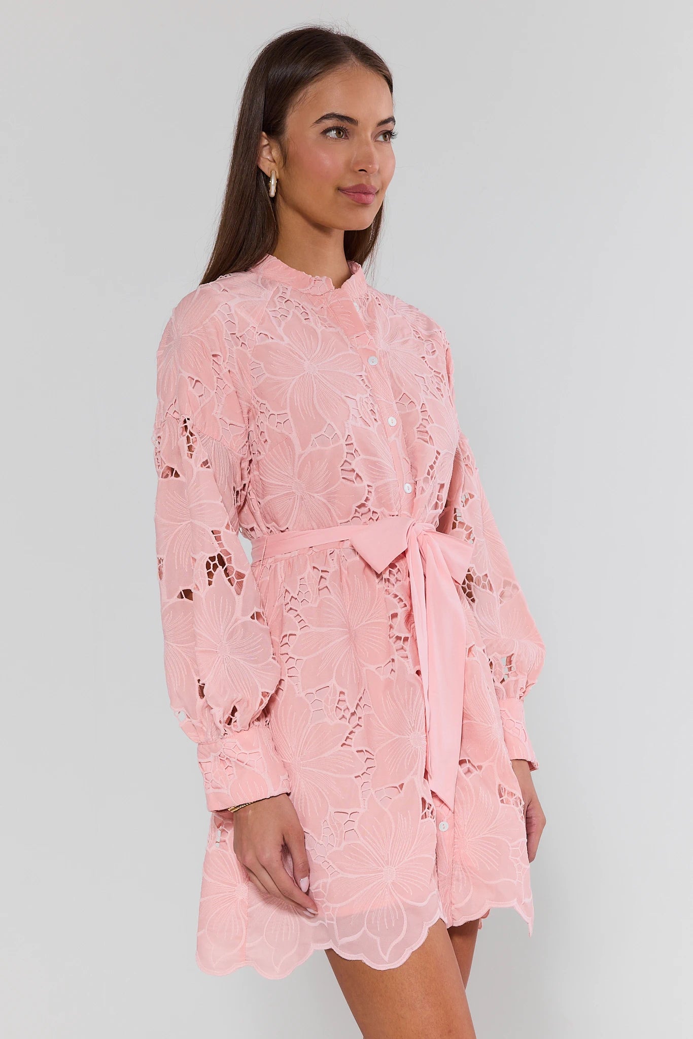 Woman wearing a pink lace dress against a plain background