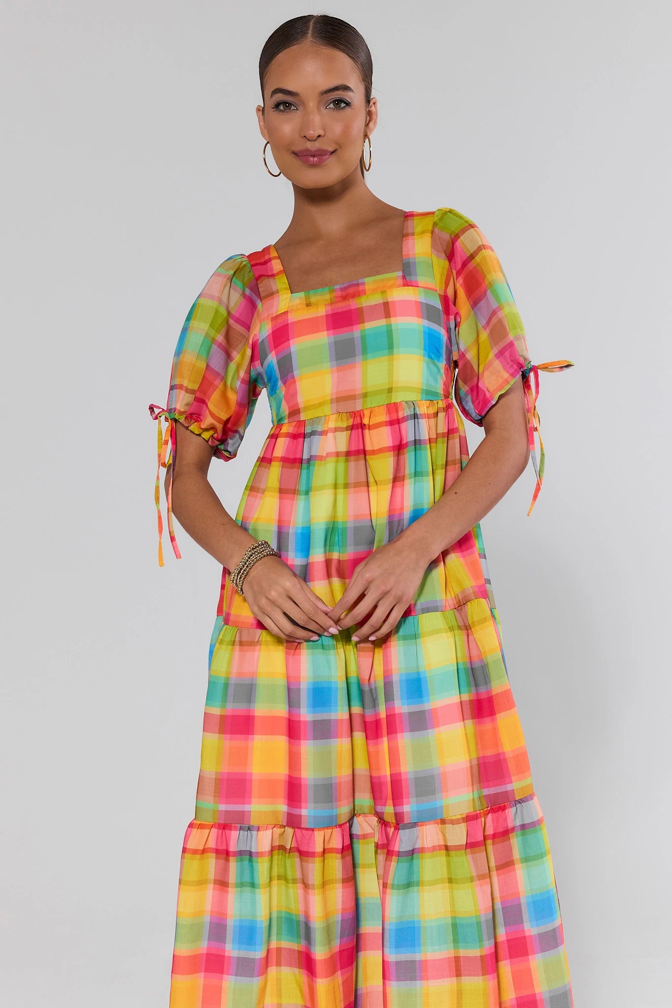 Woman wearing a colorful plaid dress against a plain background