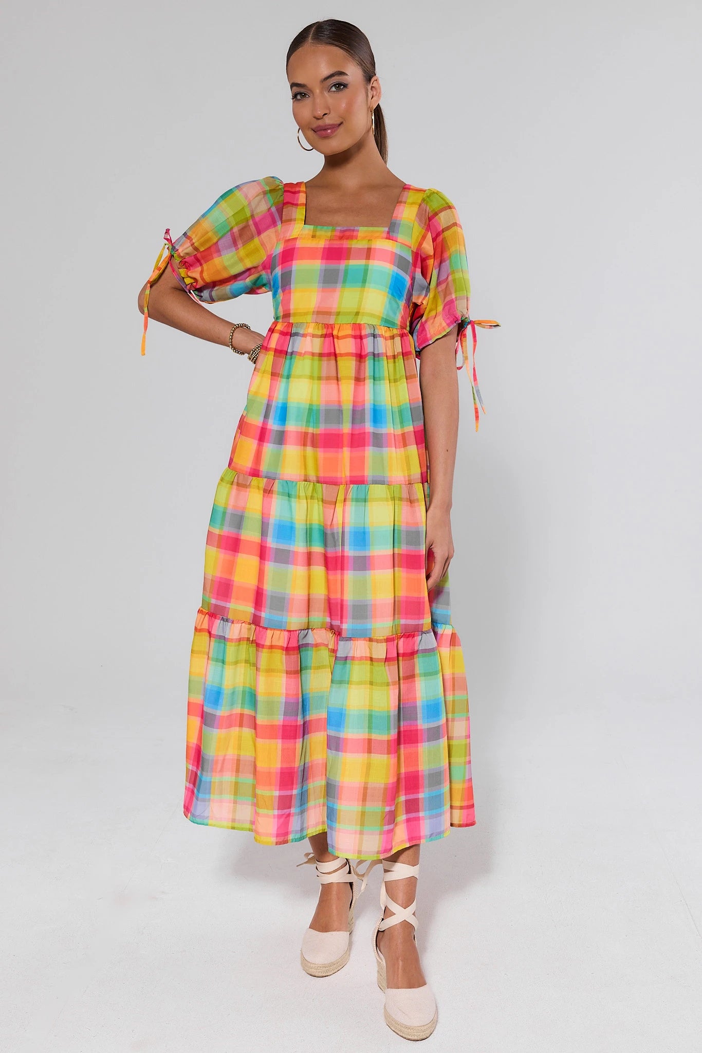 Woman wearing a colorful plaid dress and sandals on a white background