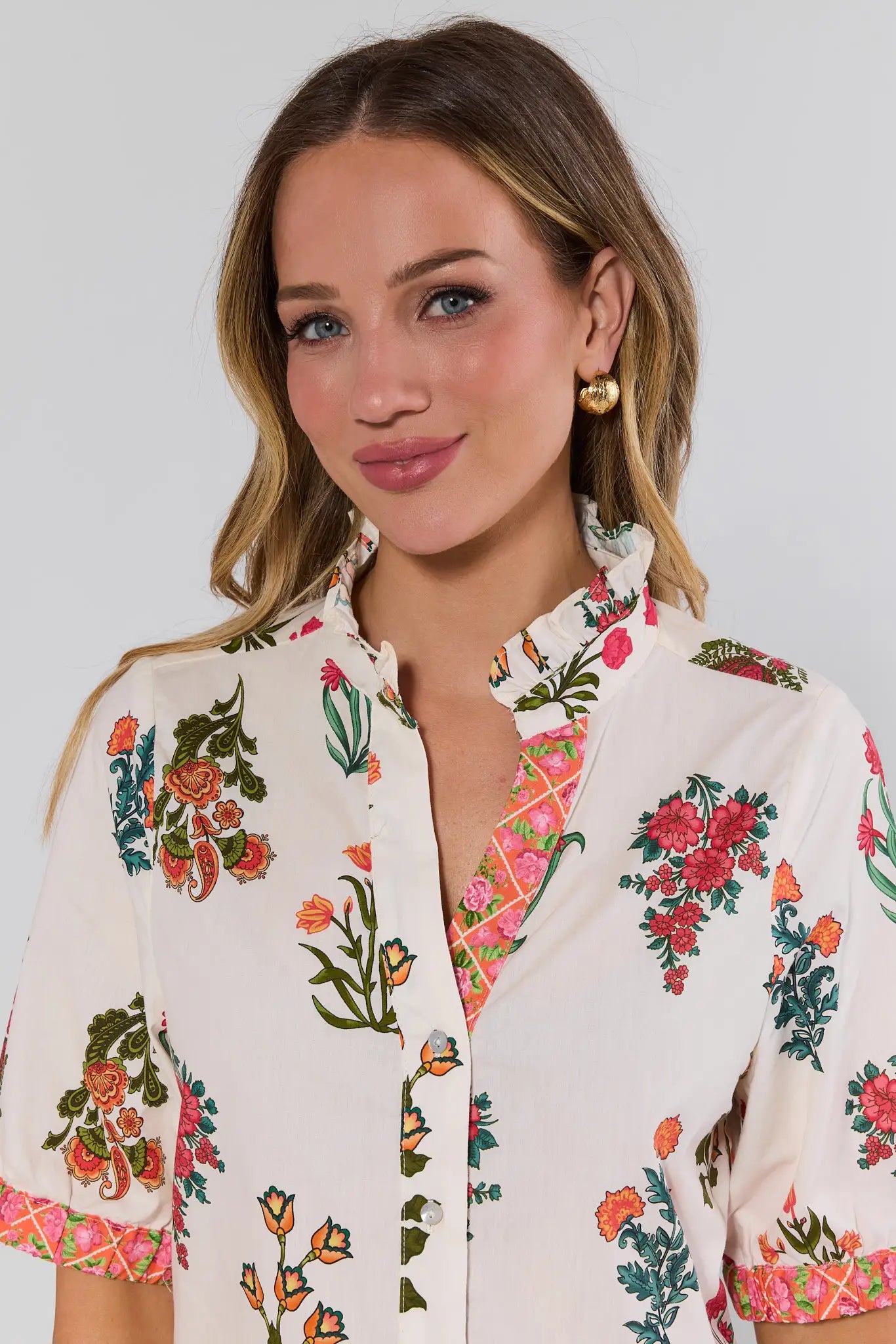 close up Woman wearing a white blouse with colorful floral patterns on a plain background