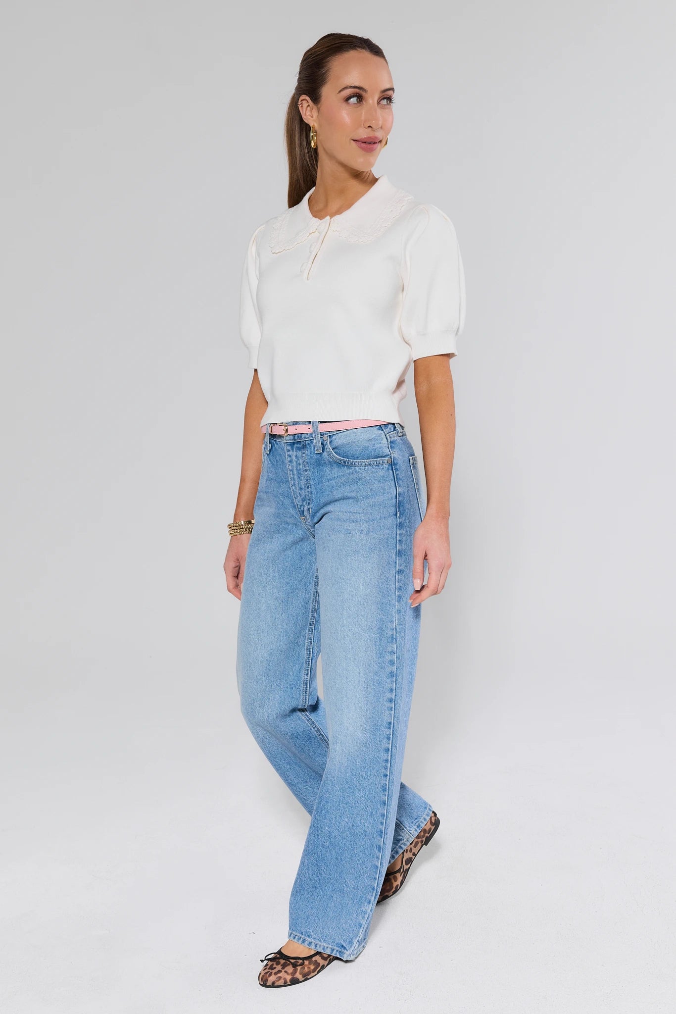 Woman wearing a white blouse and blue jeans on a plain background