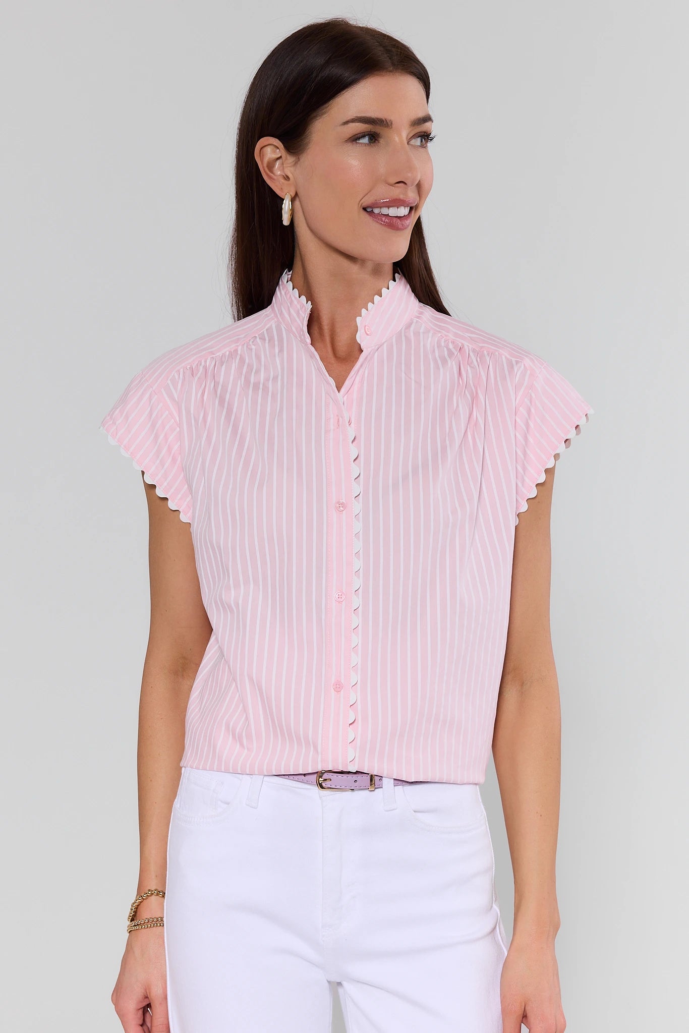 Woman wearing a light pink blouse with ruffled sleeves on a plain background