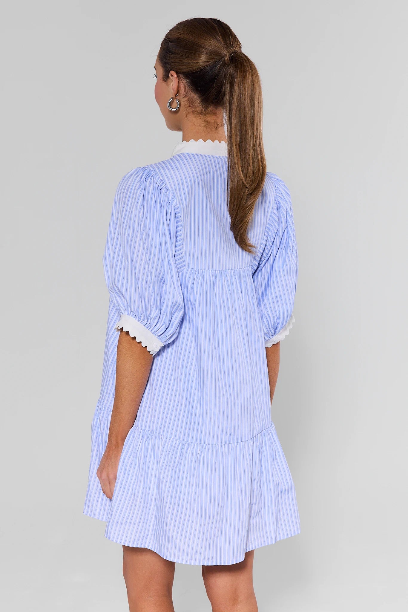 Woman wearing a blue and white striped dress against a gray background