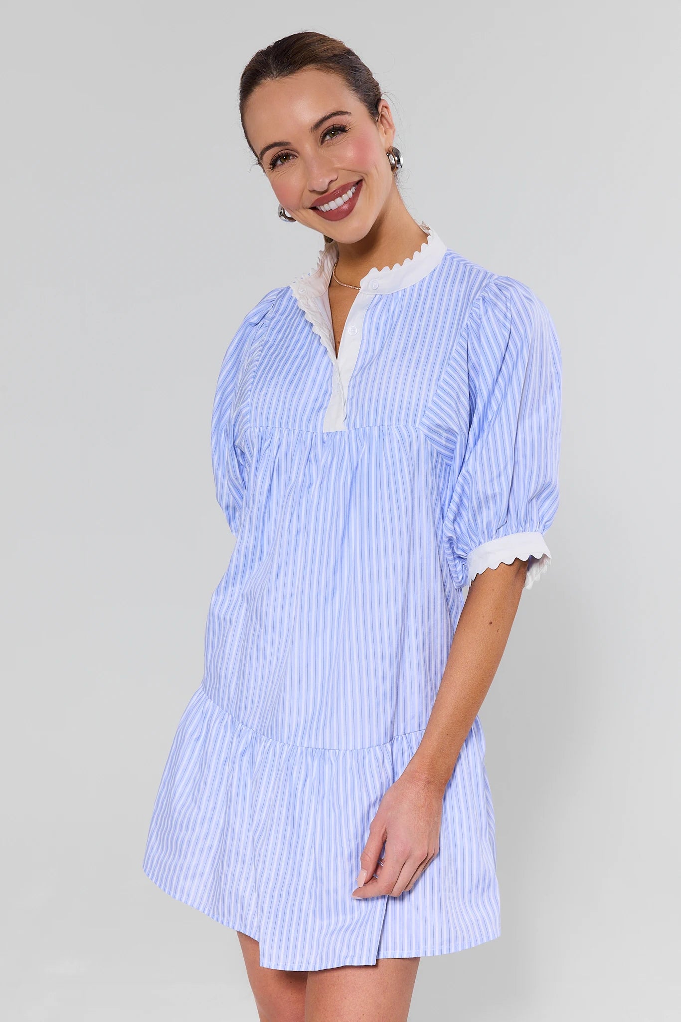 Woman wearing a blue and white striped dress with a plain background