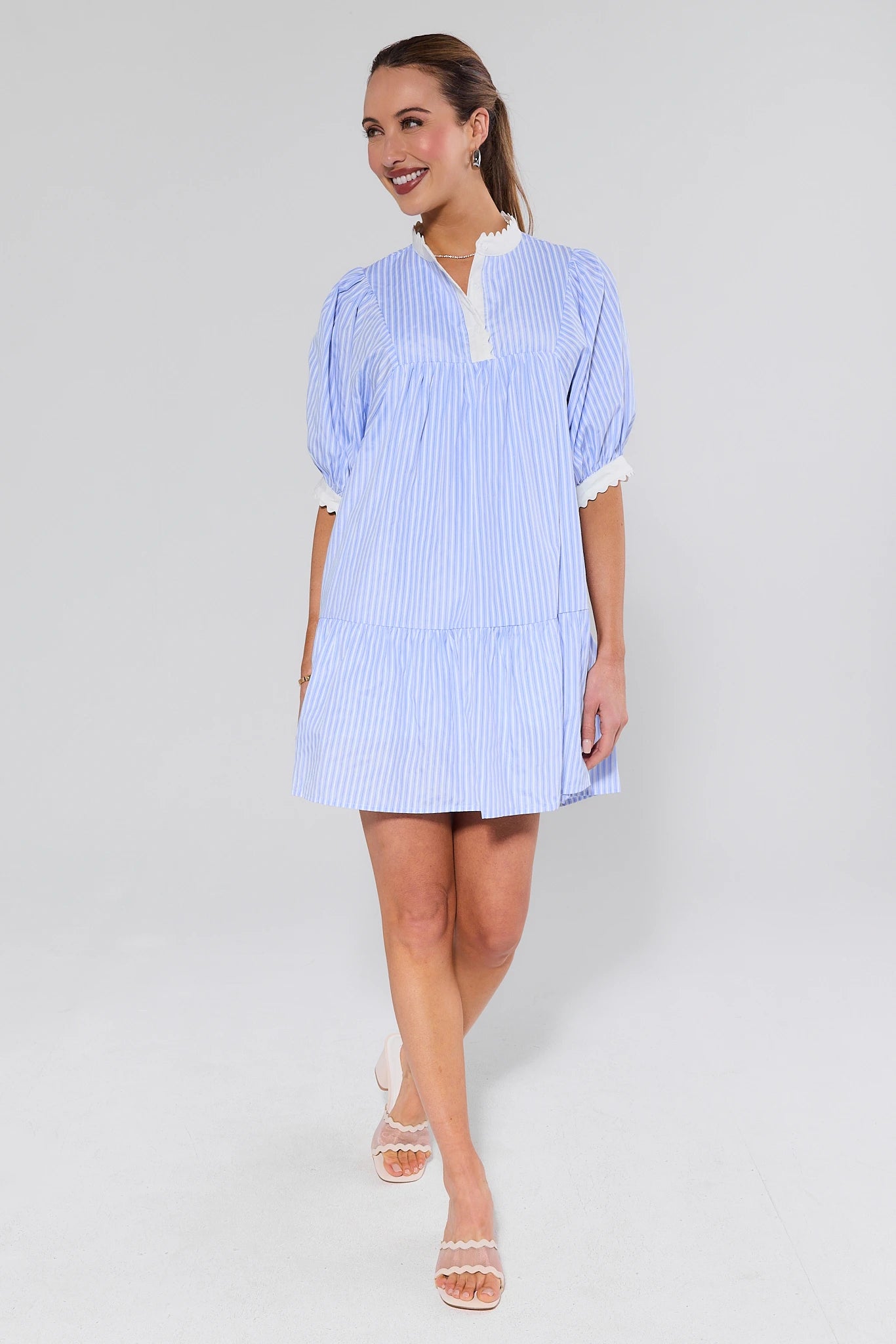 Woman wearing a blue and white striped dress on a plain background