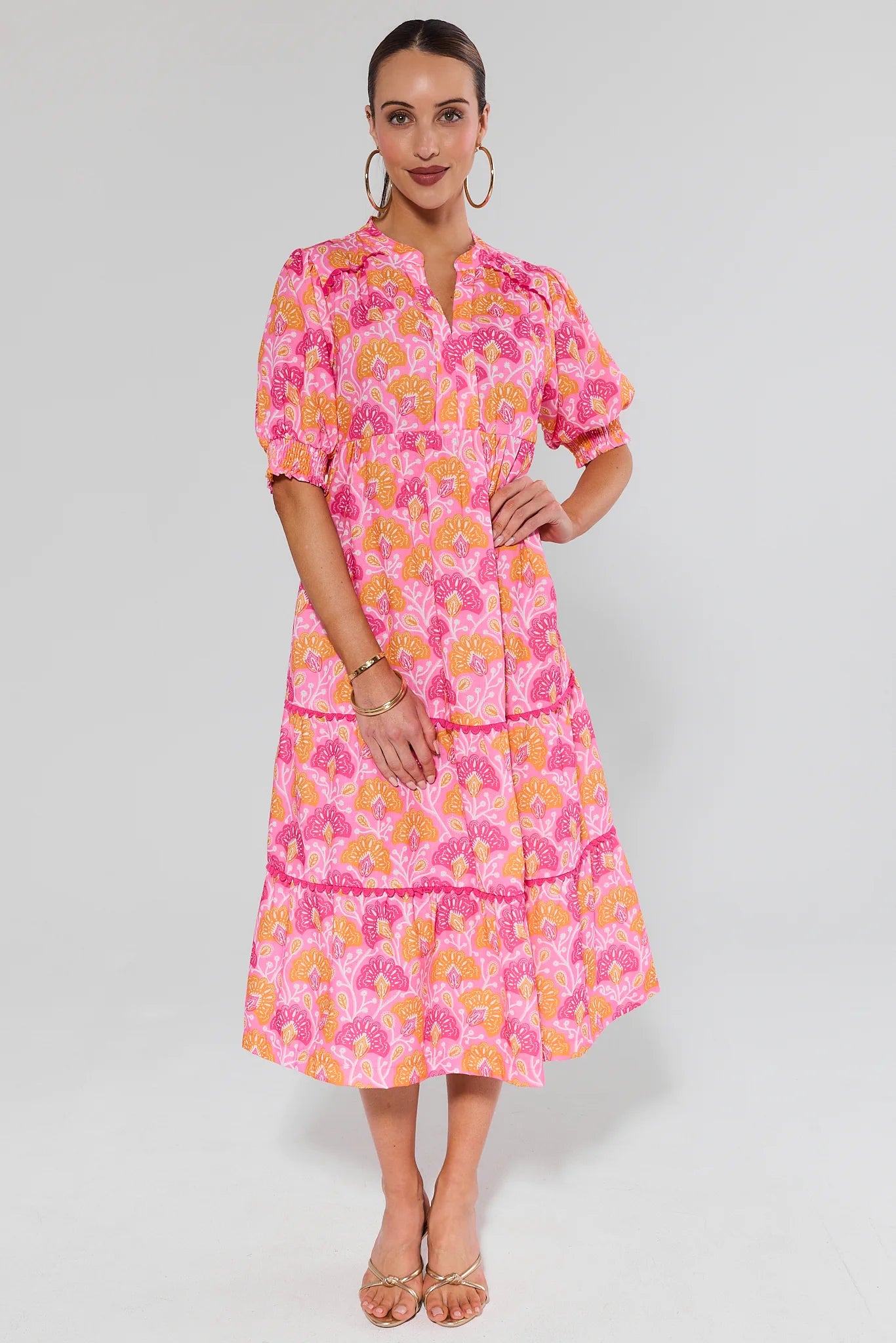Woman wearing a pink floral dress on a gray background