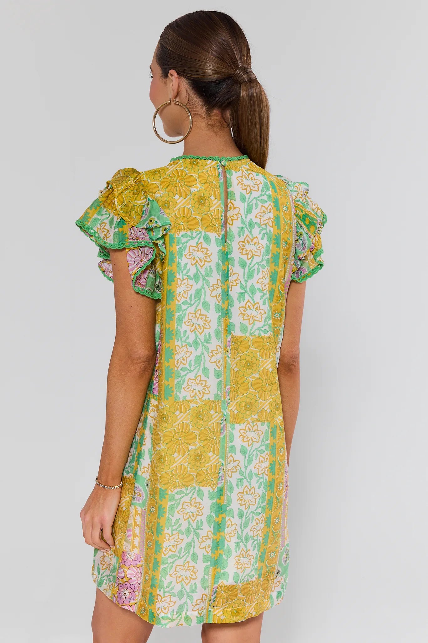 Woman wearing a yellow and green floral dress on a white background