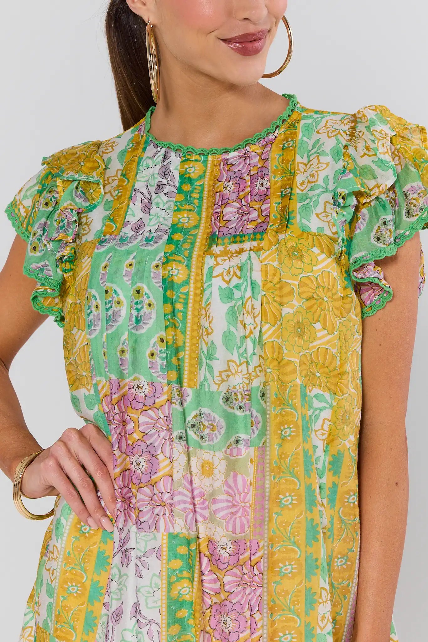 Woman wearing a colorful patterned dress with ruffled sleeves on a plain background