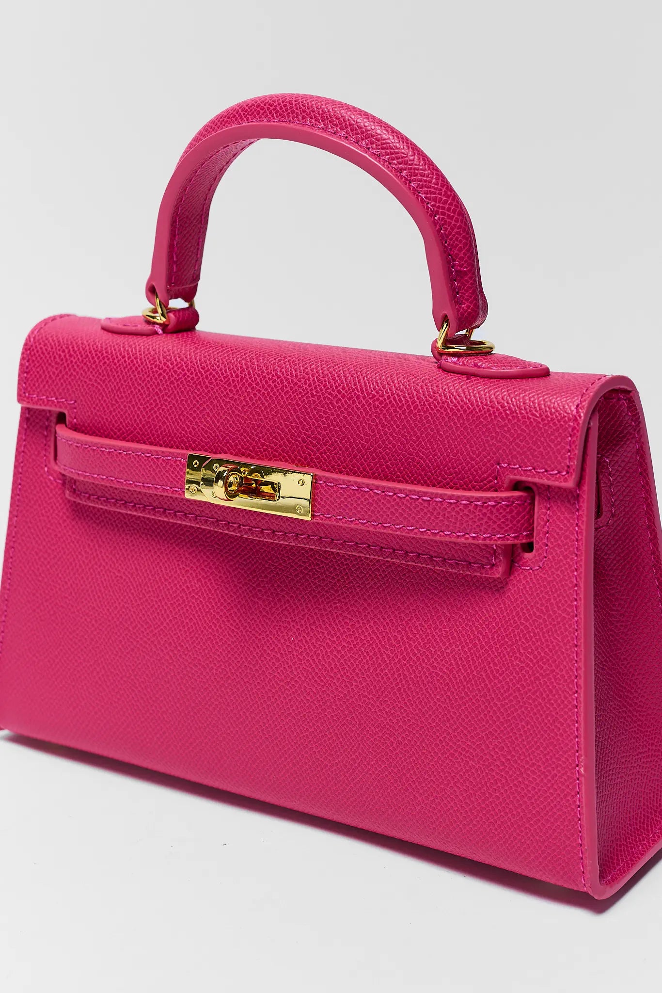 Pink handbag with gold clasp on a gray background