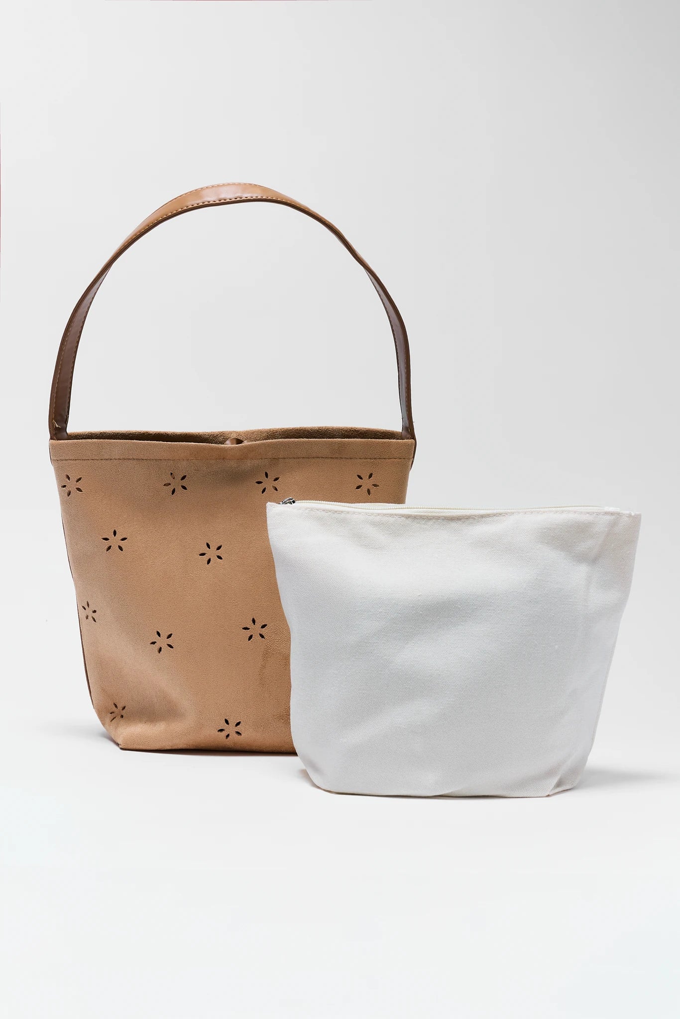 Two bags, one brown with floral cutouts and one white, on a light gray background.