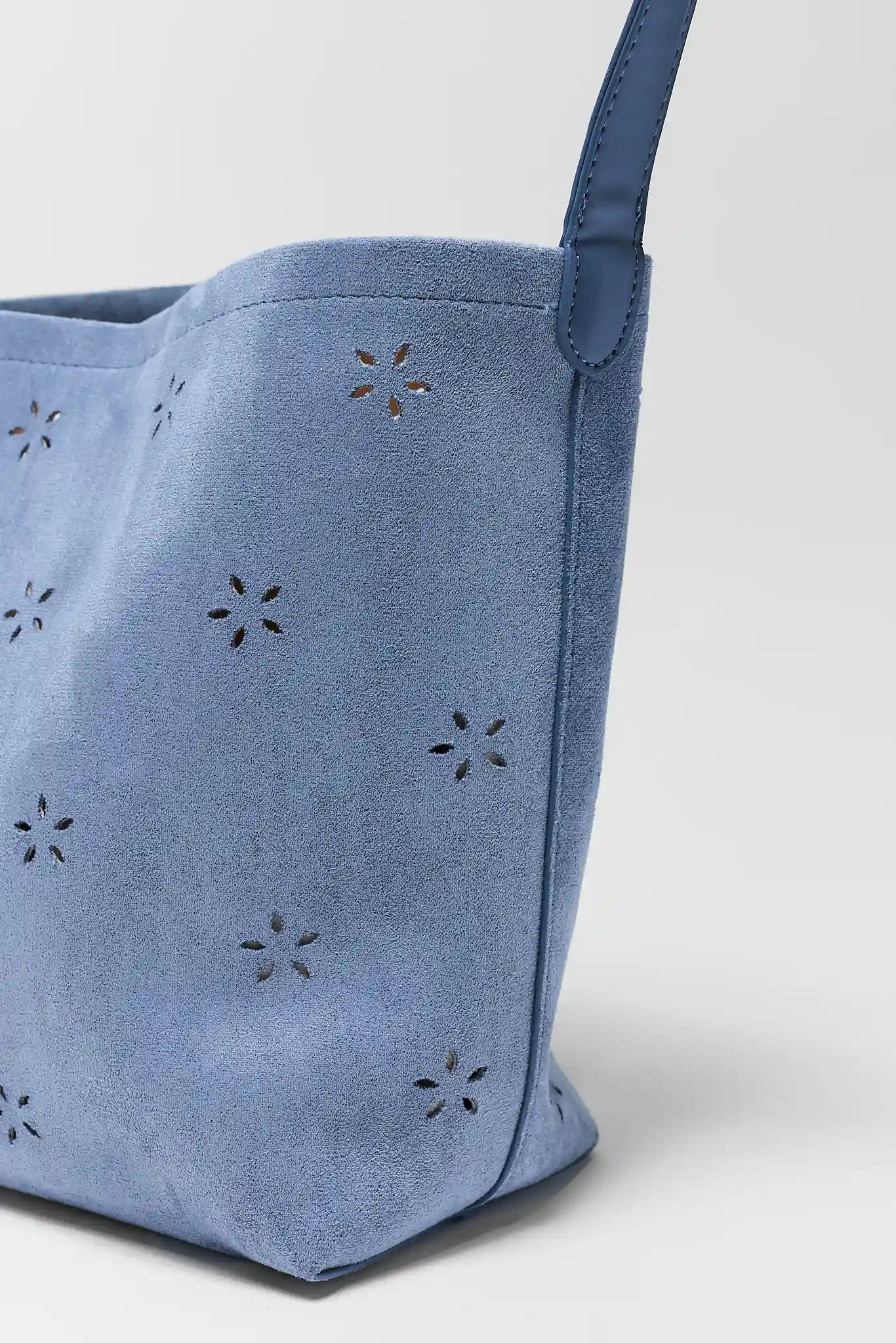 Blue tote bag with star-shaped cutouts on a light gray background