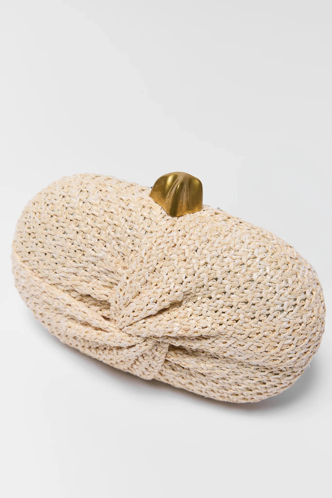 close up tan woven rafia handbag on a plain background