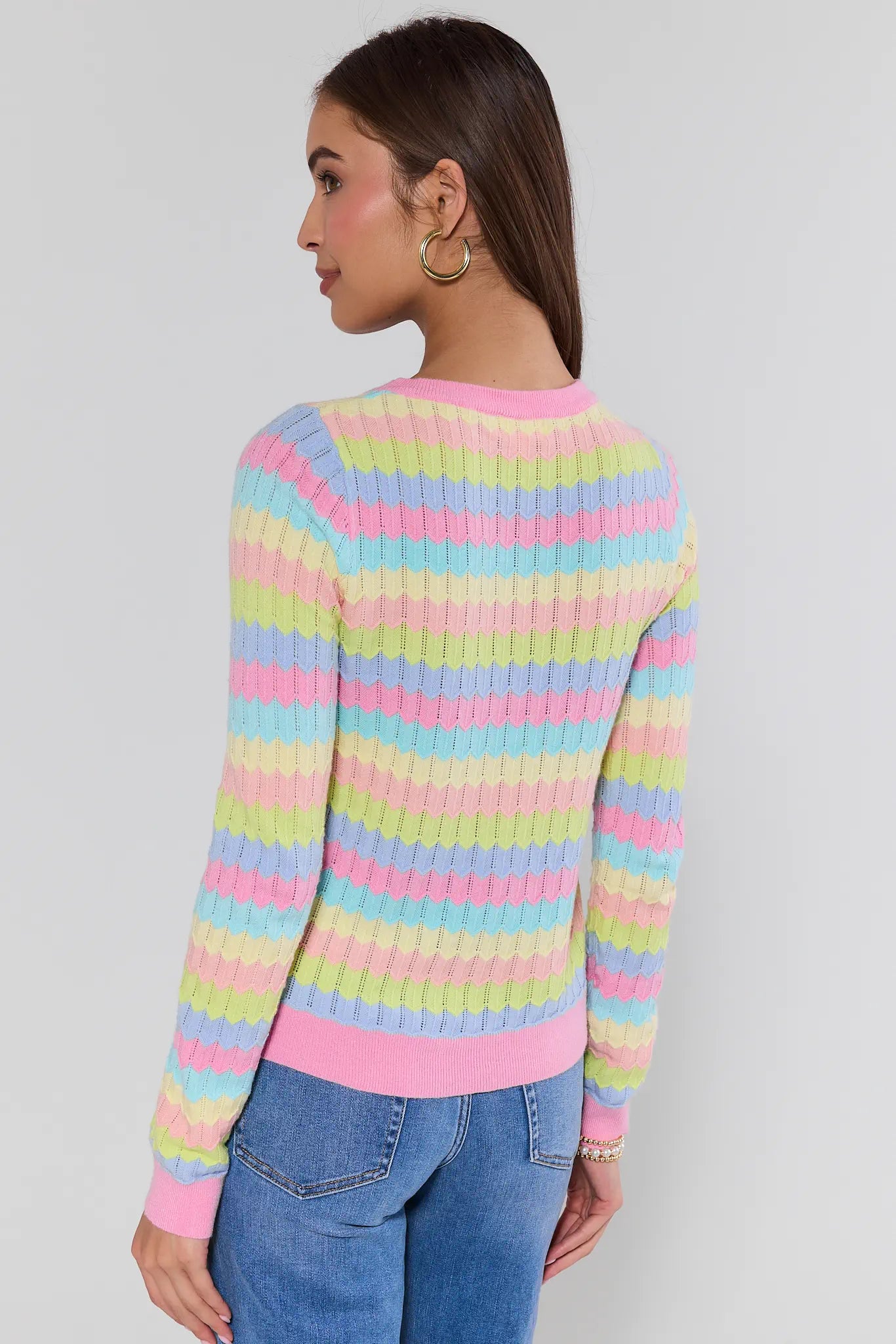view 2: Woman wearing a colorful striped sweater against a plain background