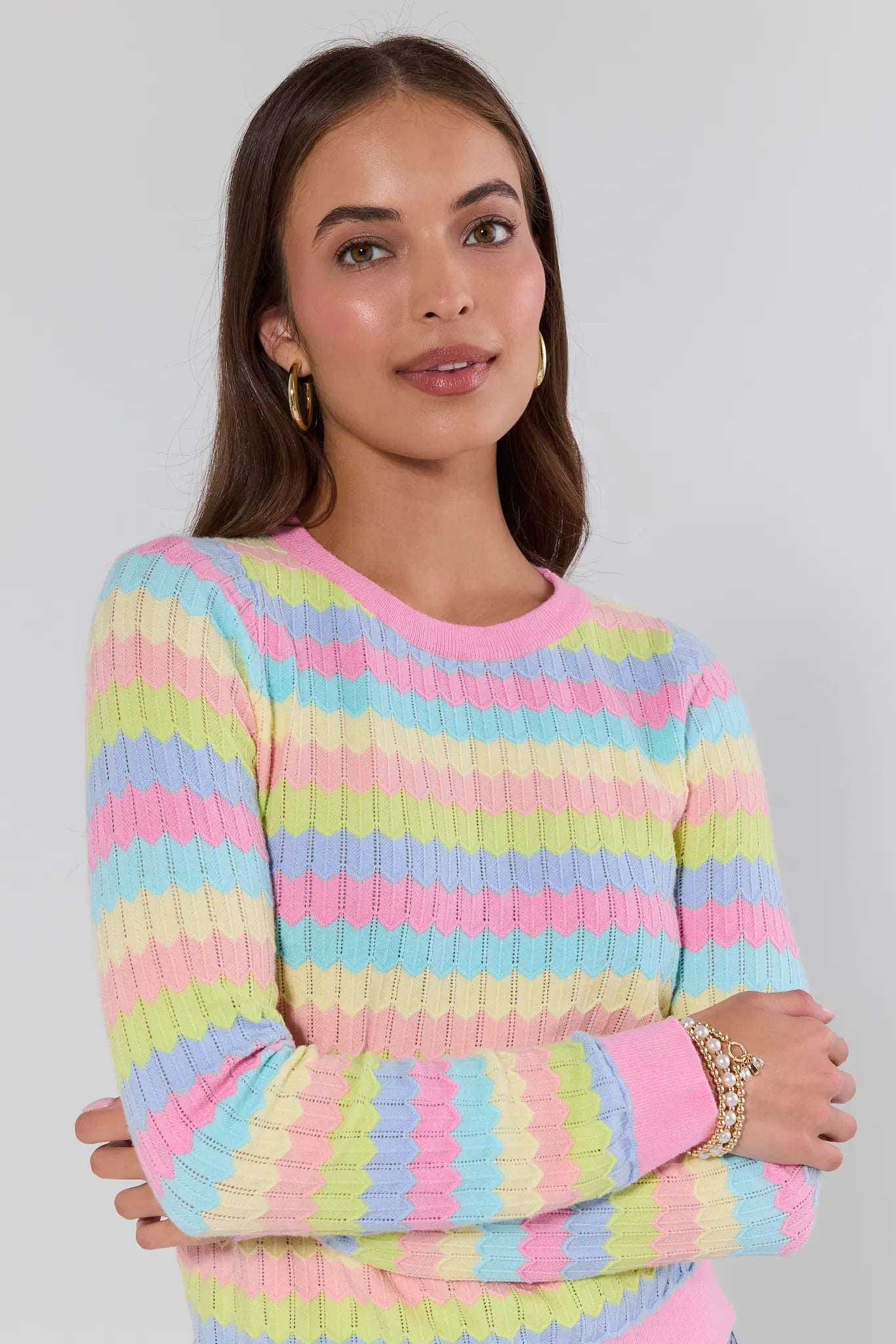 Woman wearing a pastel striped sweater against a gray background