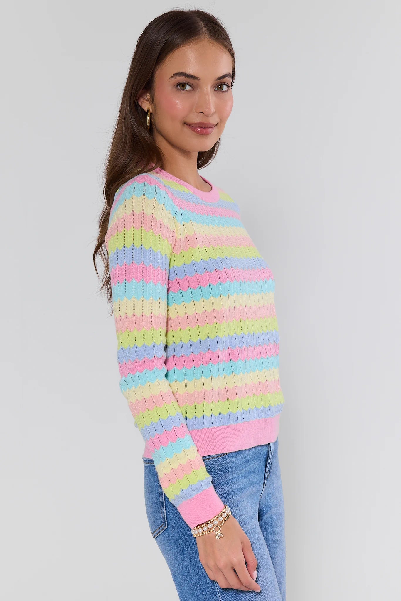 Woman wearing a colorful striped sweater against a plain background