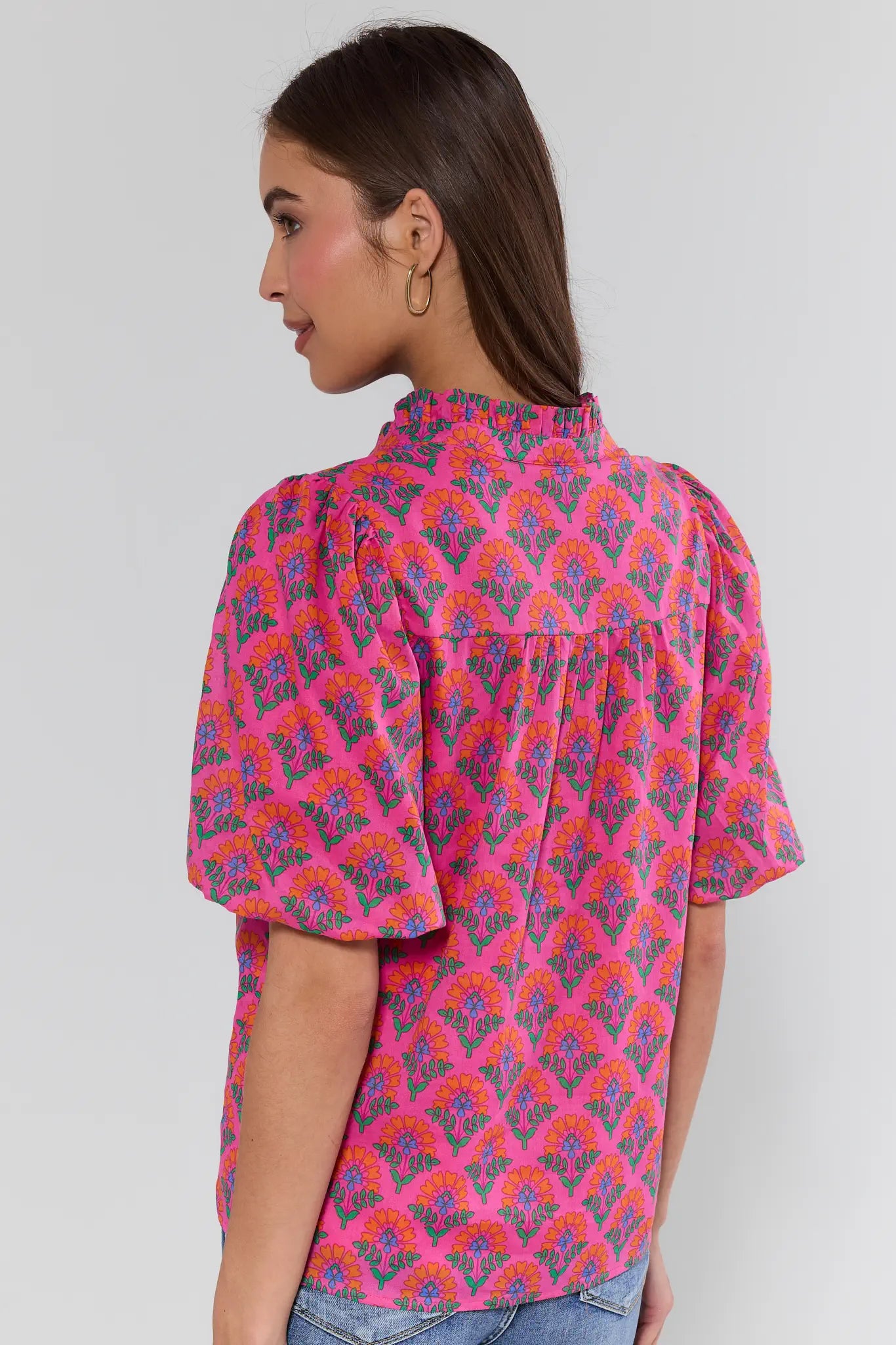 Woman wearing a colorful patterned blouse against a plain background
