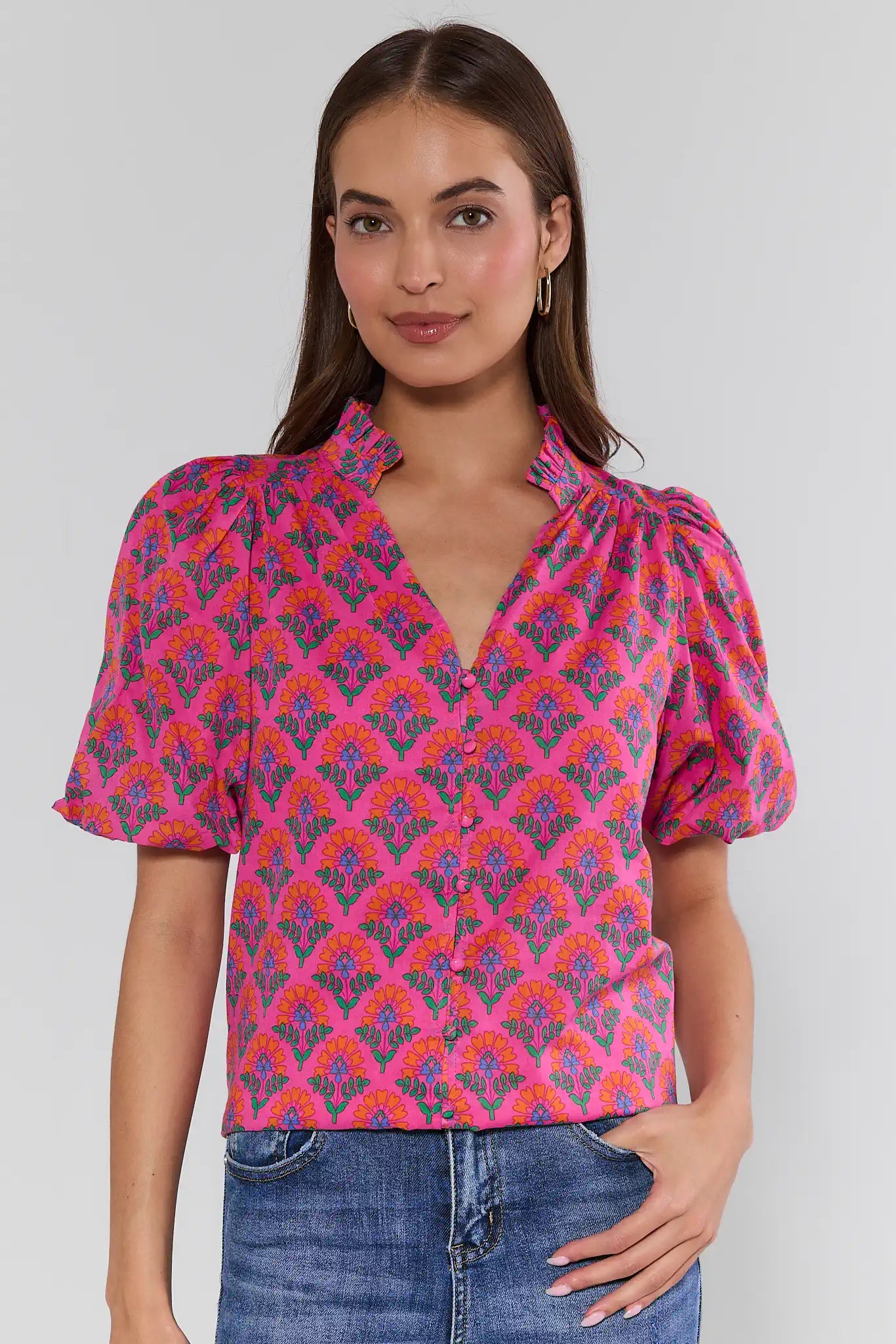 Woman wearing a colorful patterned blouse with short sleeves on a plain background