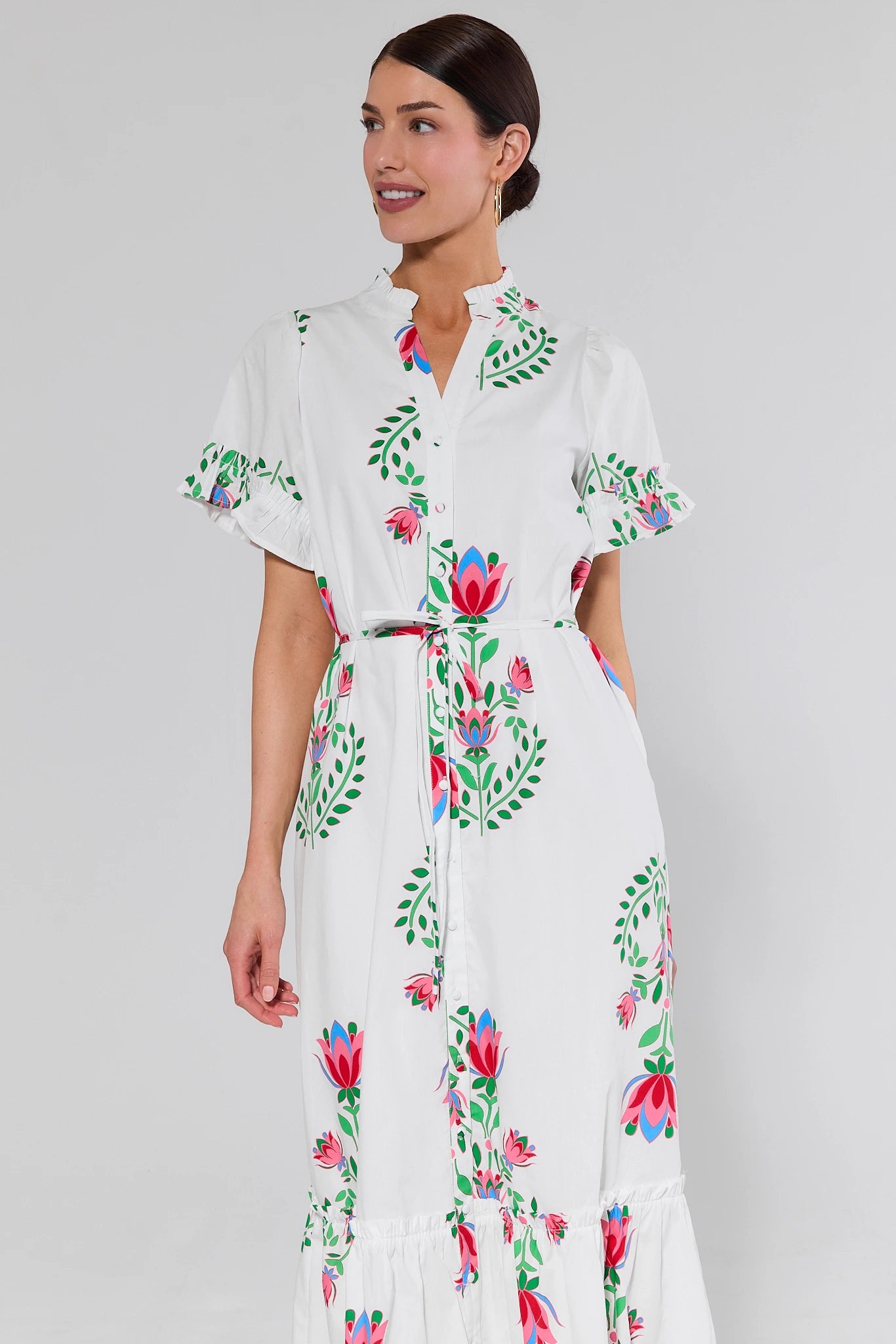 Woman wearing a white printed dress with colorful floral patterns on a plain background