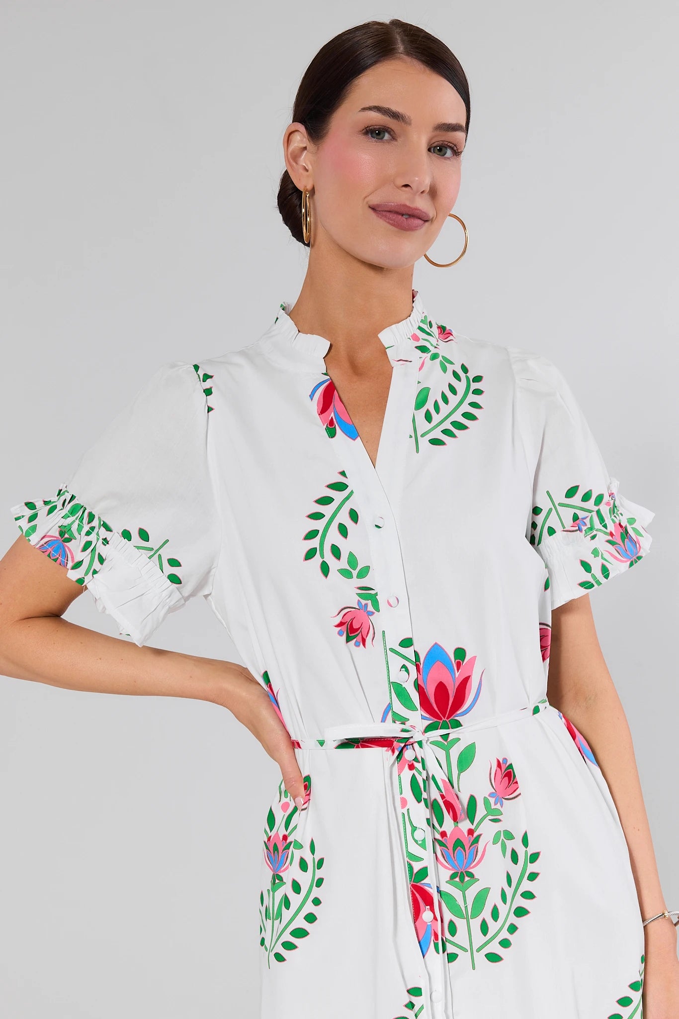 close up Woman wearing a white dress with floral embroidery on a plain background