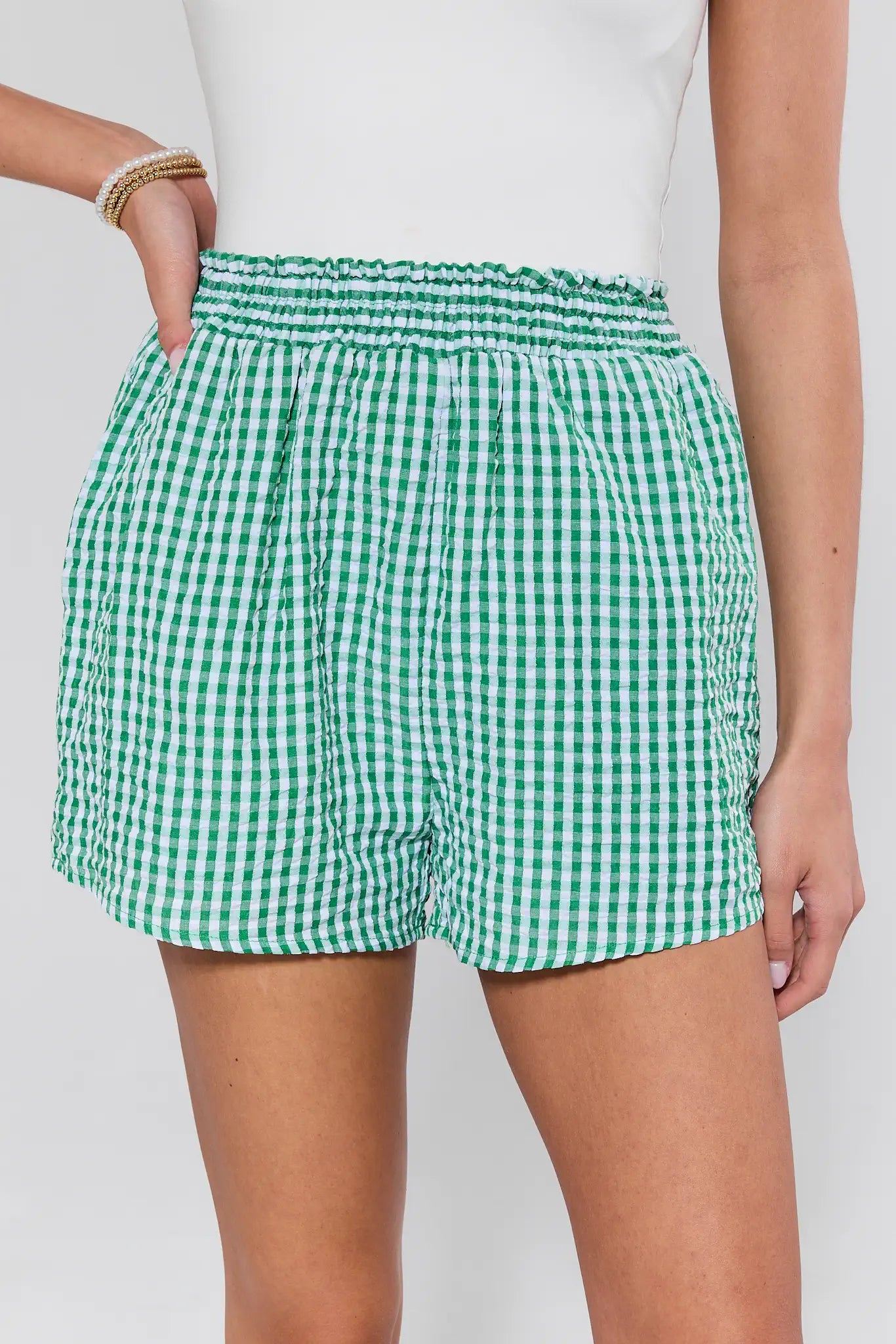 Green and white checkered shorts worn by a person on a plain background