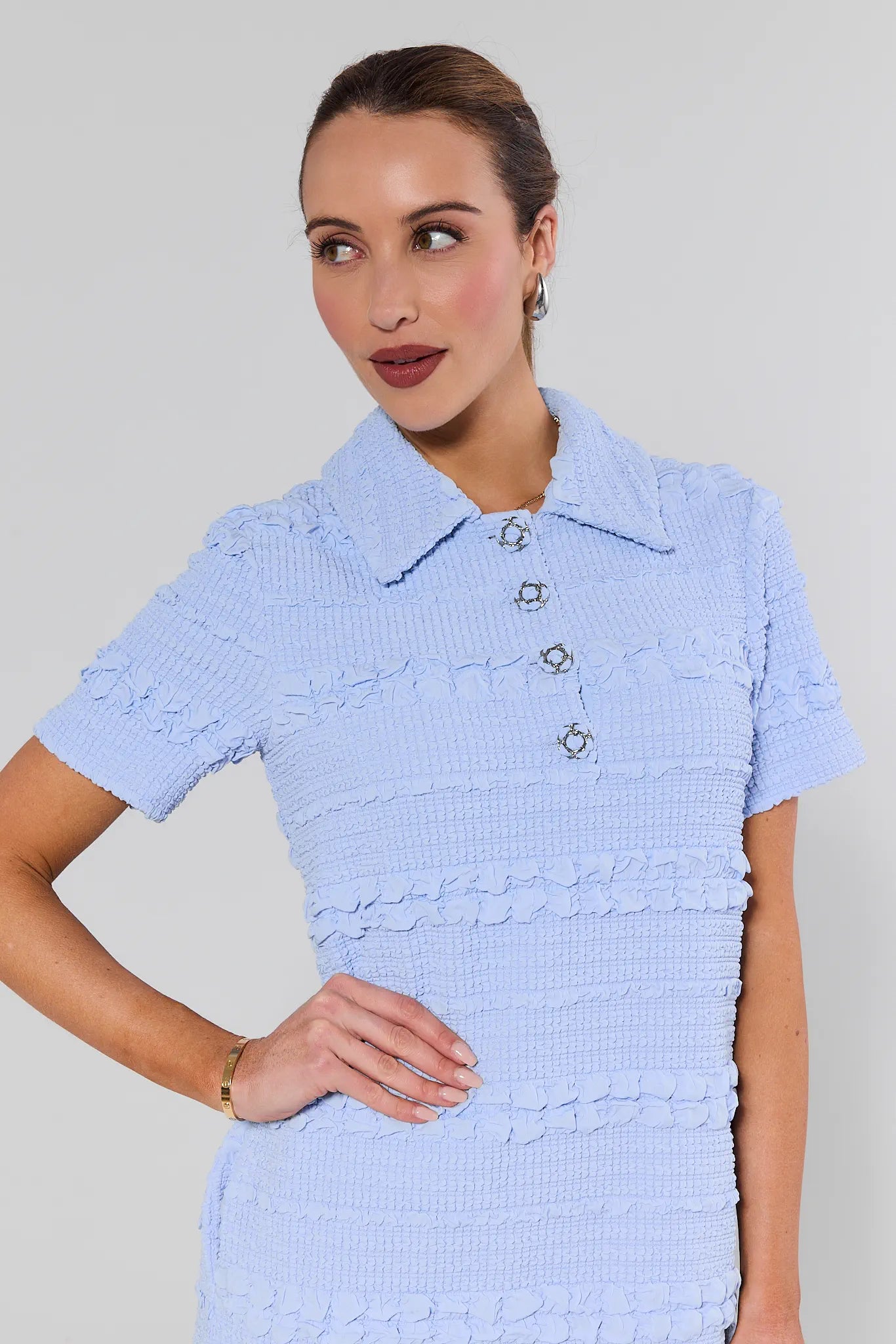 Woman wearing a light blue dress with a textured pattern against a plain background