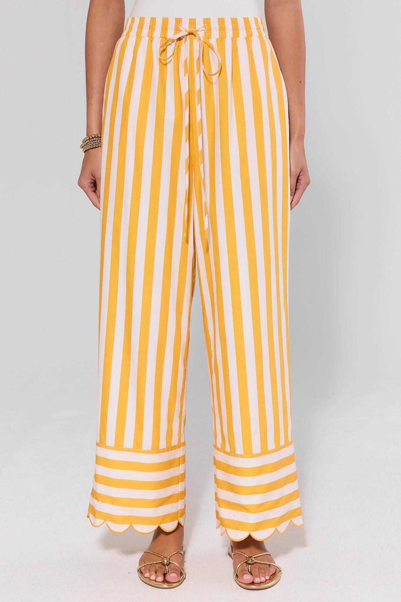 Yellow and white striped pants worn by a person on a white background
