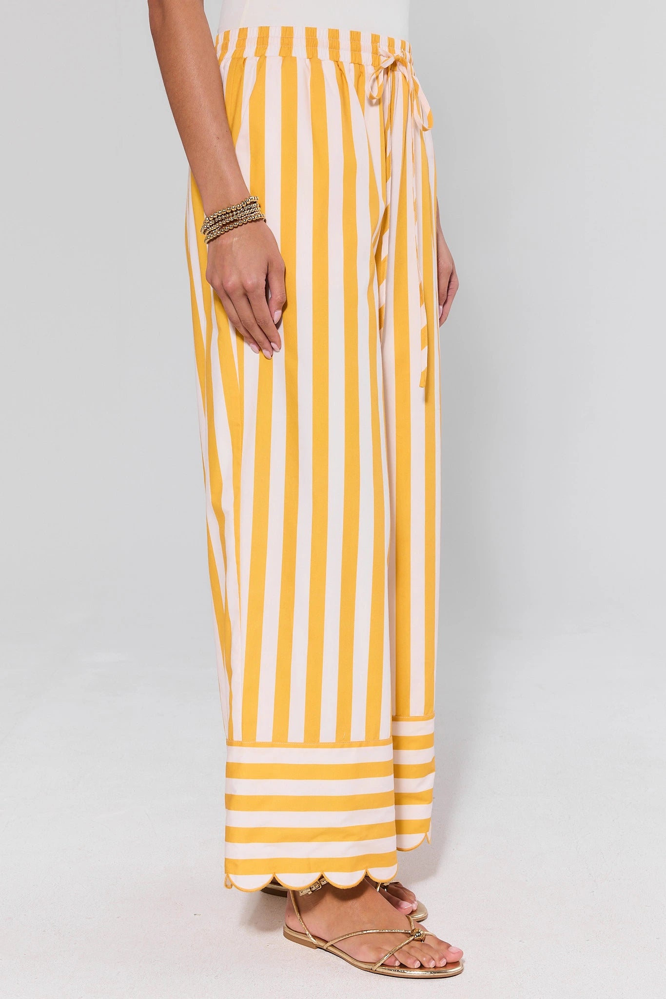 side shot Yellow and white striped pants worn by a person on a plain background