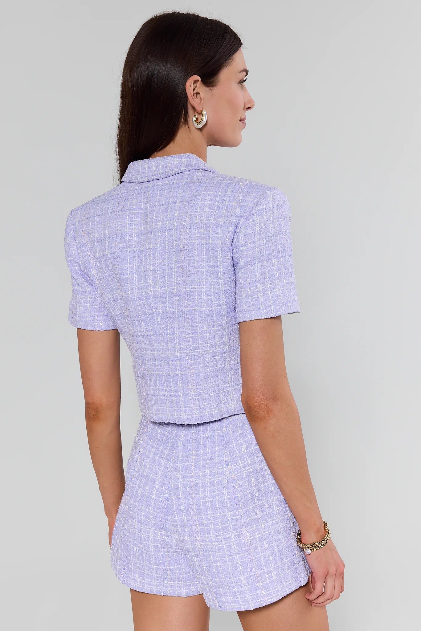 Woman wearing a light purple checkered dress against a plain background