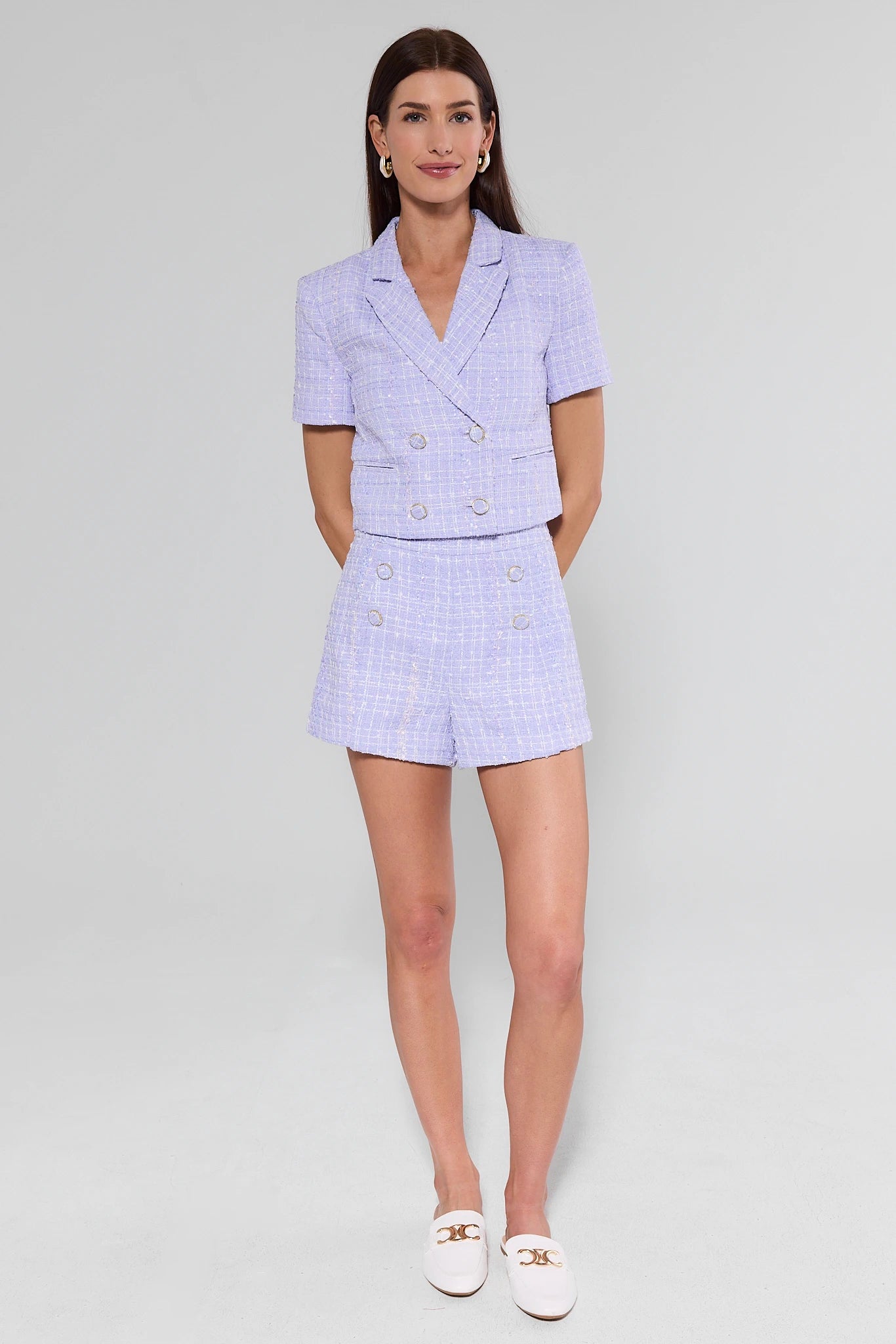 Woman wearing a light purple checkered suit on a white background