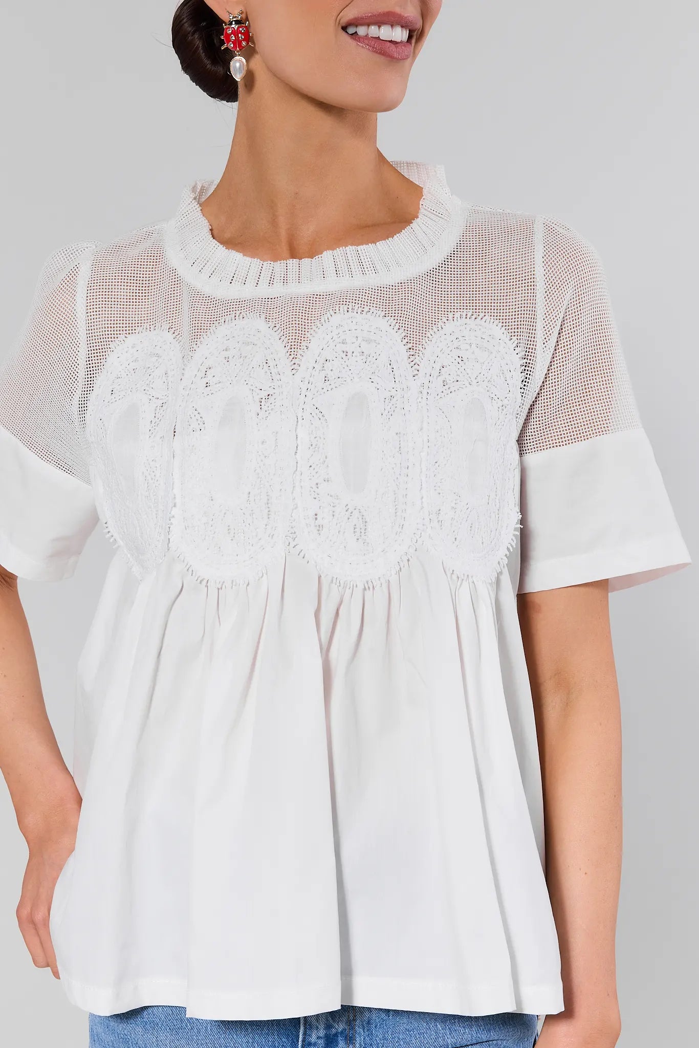 close up Woman wearing a white blouse with lace details on a plain background